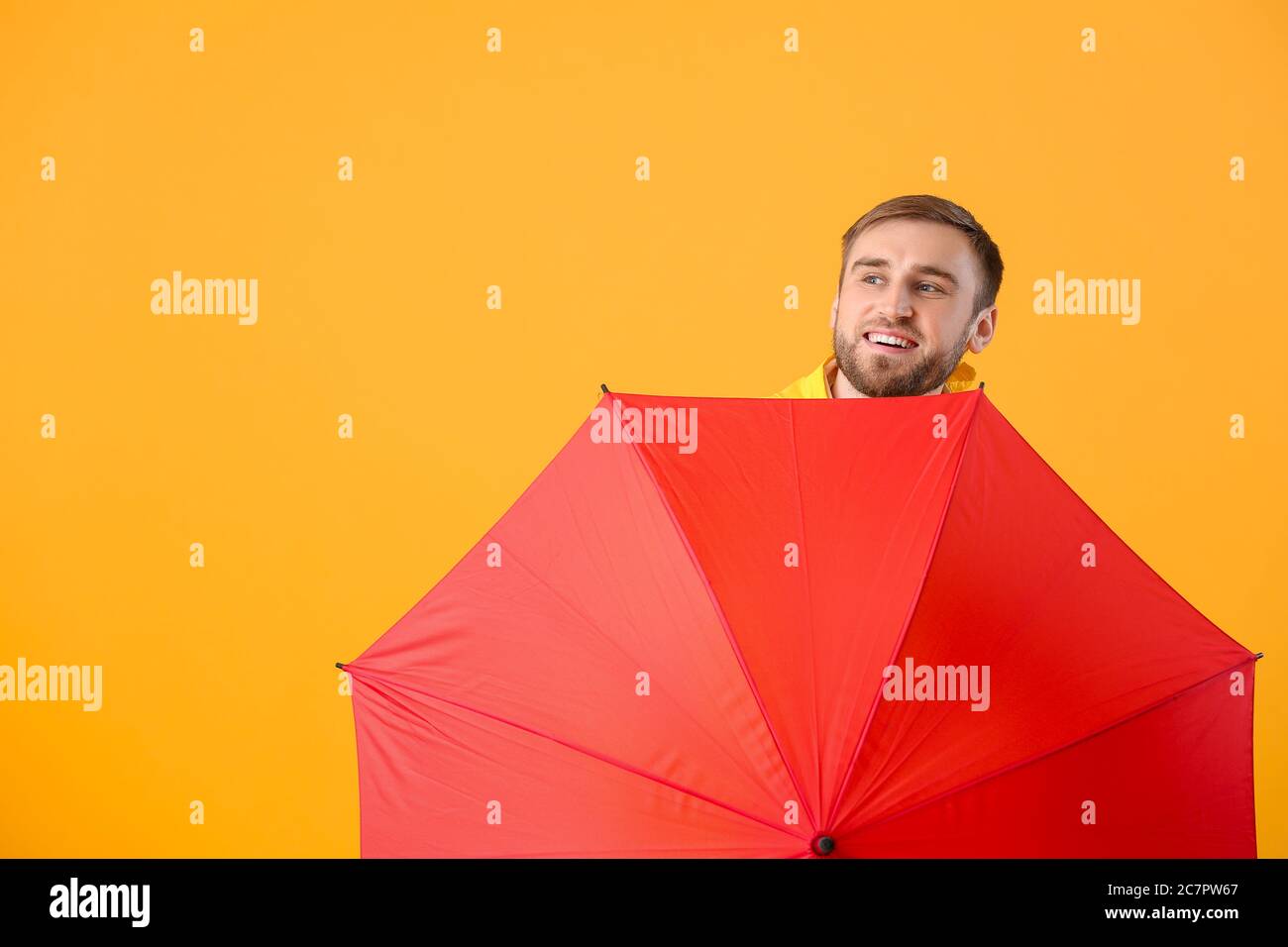 Handsome young man with umbrella on color background Stock Photo - Alamy