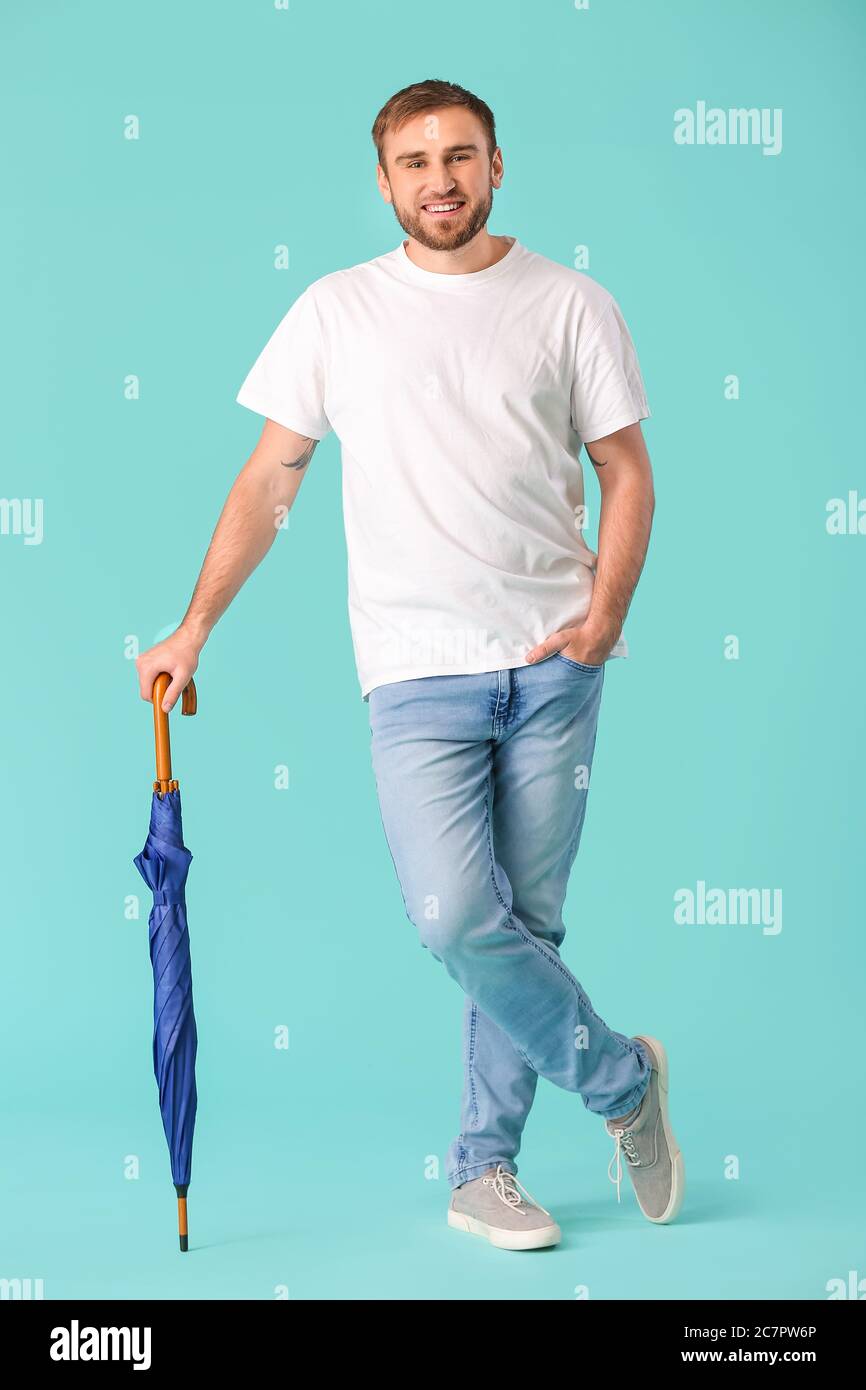 Handsome young man with umbrella on color background Stock Photo - Alamy