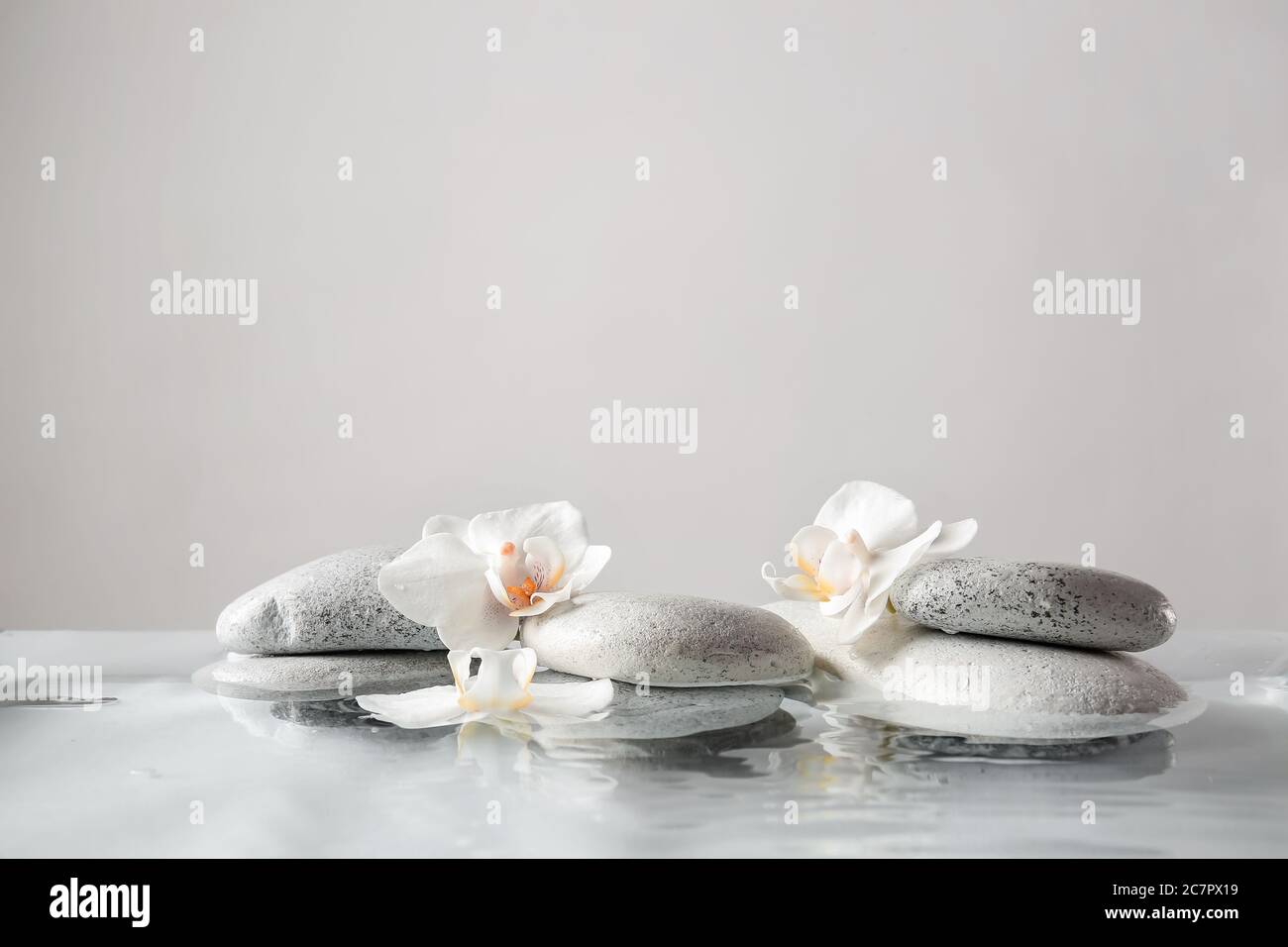 Spa stones and flowers in water against light background Stock Photo ...