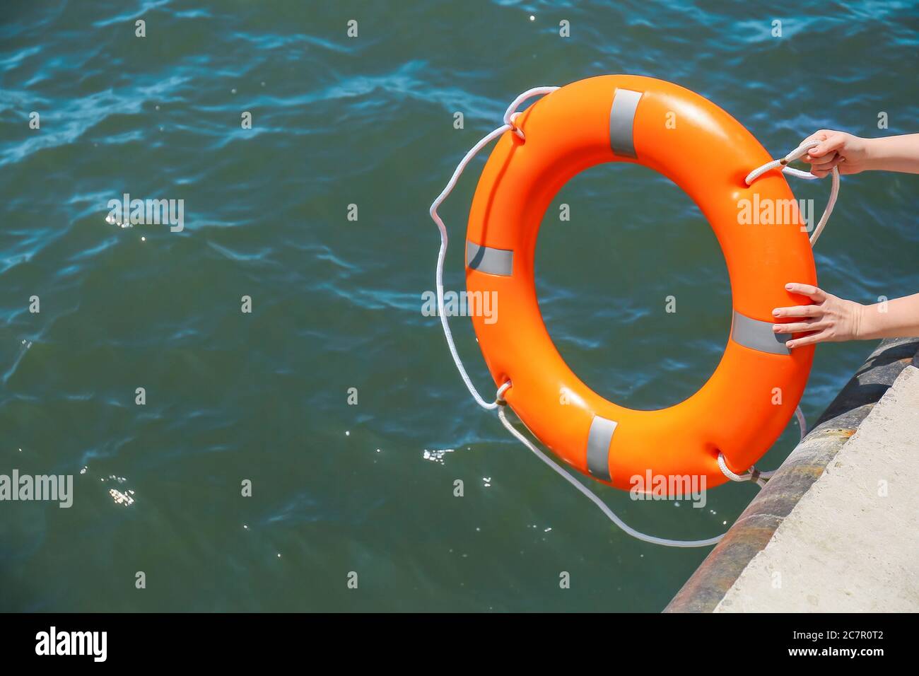 Woman throwing lifebuoy ring on water Stock Photo Alamy