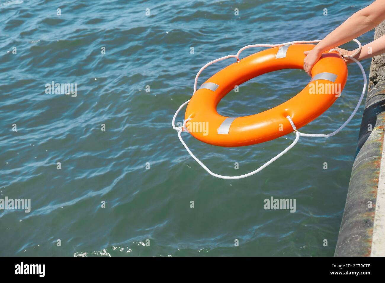 Woman throwing lifebuoy ring on water Stock Photo Alamy