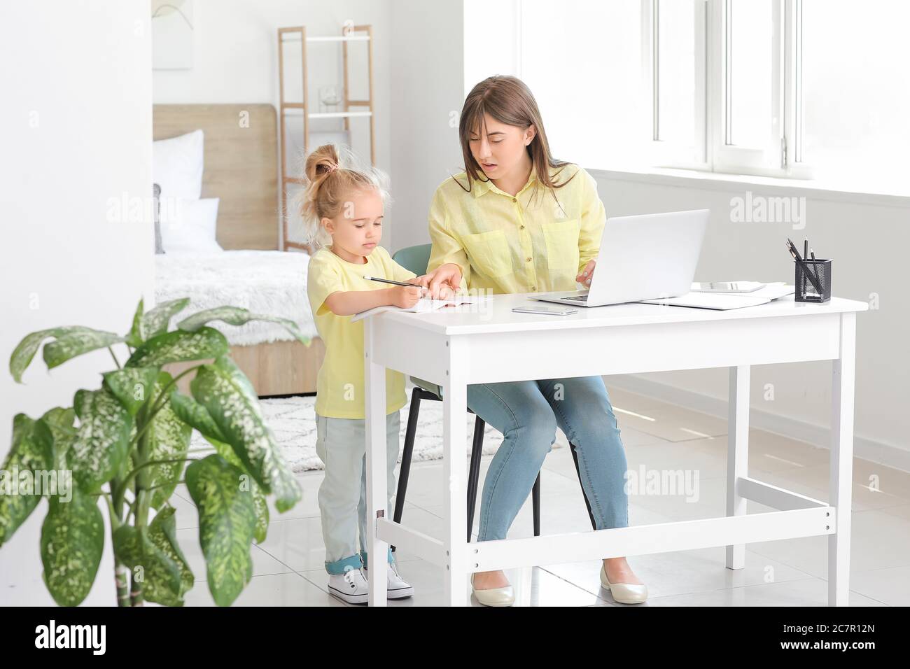 Working mother with her little daughter at home Stock Photo
