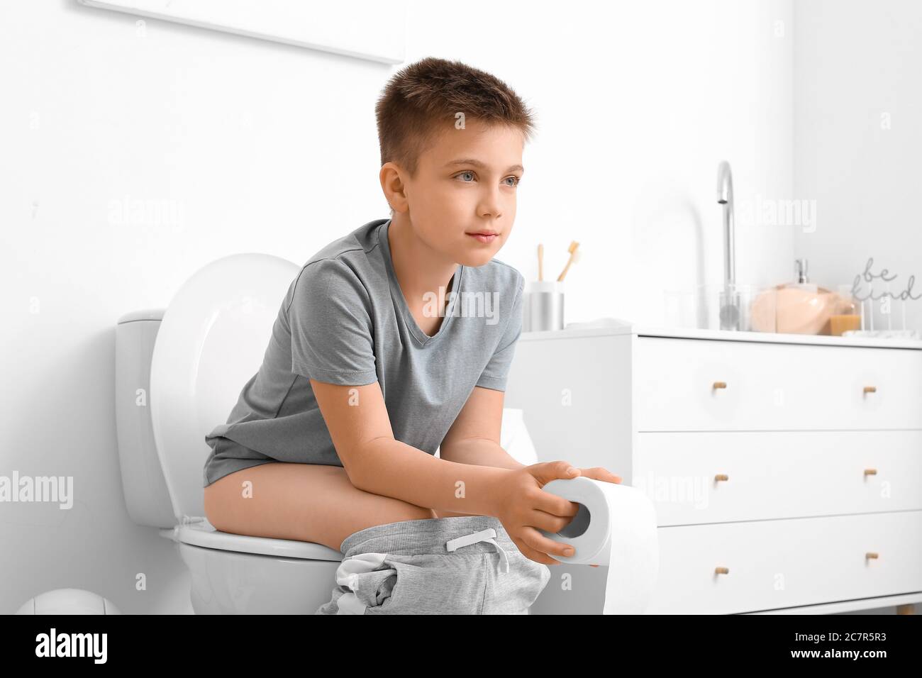 Little boy sitting on toilet bowl in restroom Stock Photo Alamy