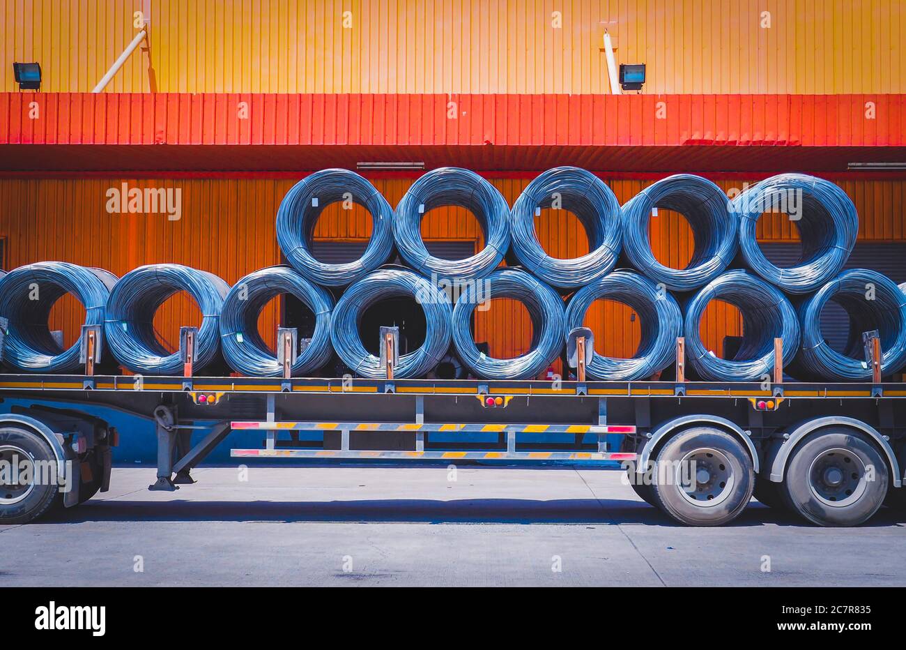 Coils of steel wire rod on truck trailer at industrial zone. Truck receives steel wire rod from warehouse container unstuffing area. Stock Photo