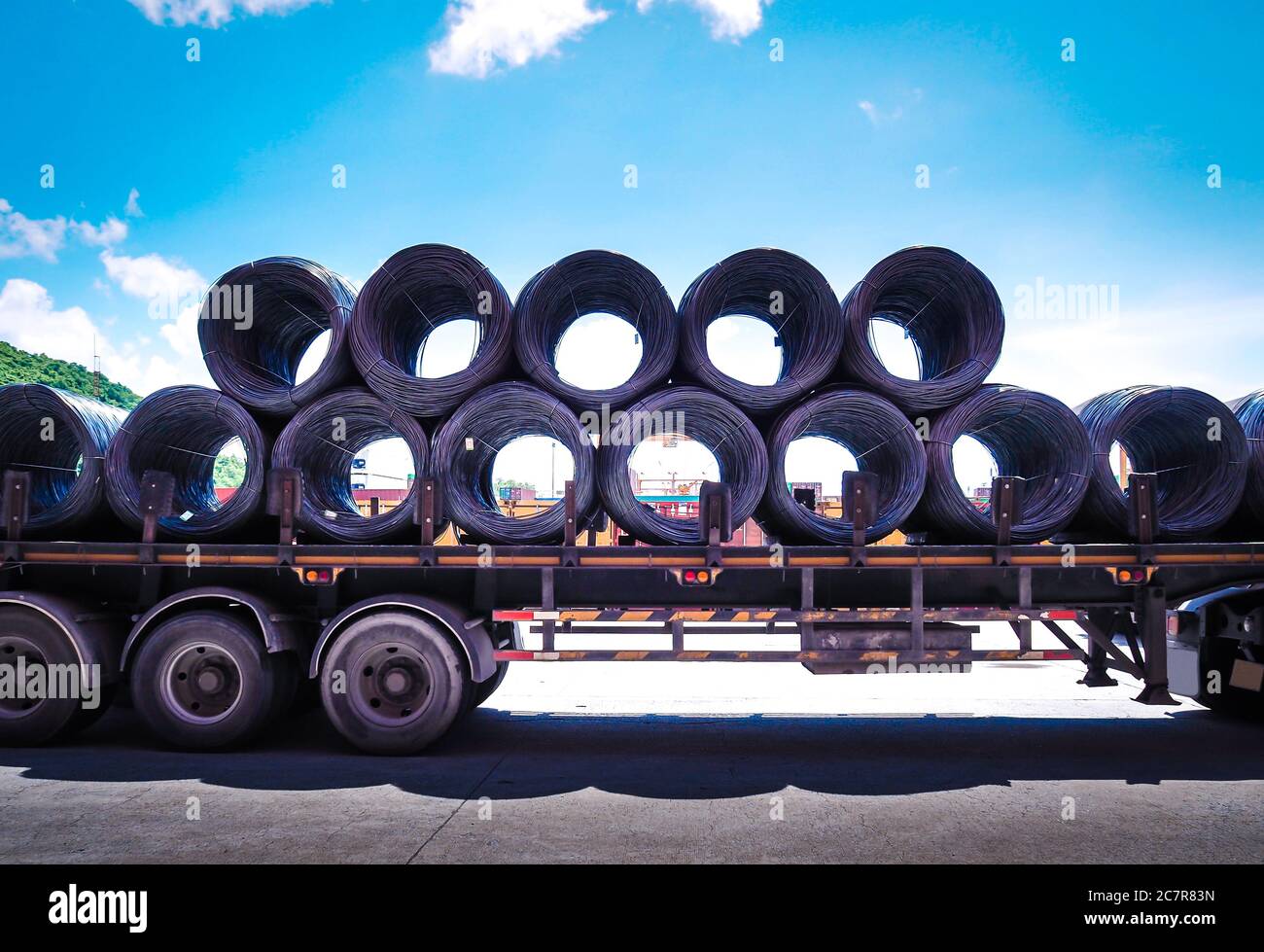 Coils of steel wire rod on truck trailer at industrial zone. Truck receives steel wire rod from warehouse container unstuffing area. Stock Photo