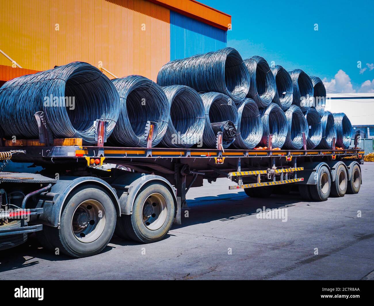 Coils of steel wire rod on truck trailer at industrial zone. Truck receives steel wire rod from warehouse container unstuffing area. Stock Photo