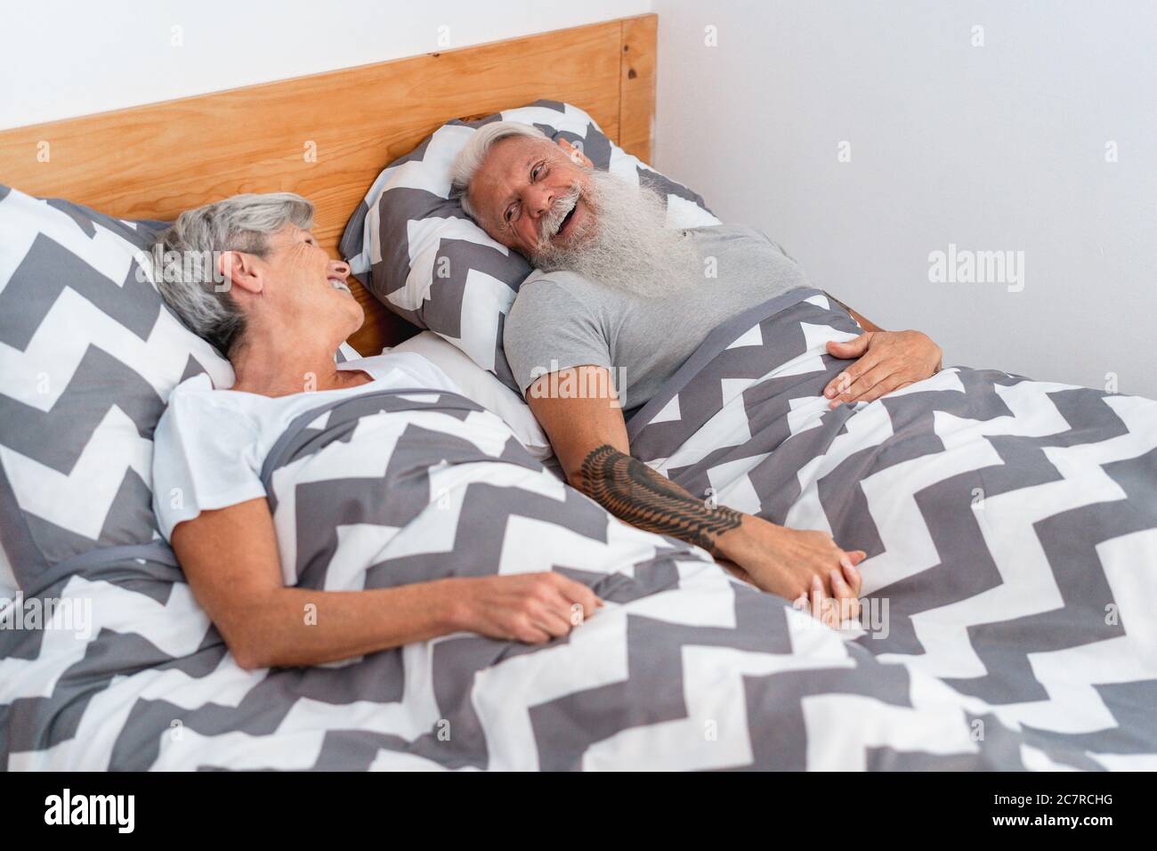 Senior couple under the blanket at home - Old man and attractive mature woman are spending time together while lying in bed - Happy people and joyful Stock Photo