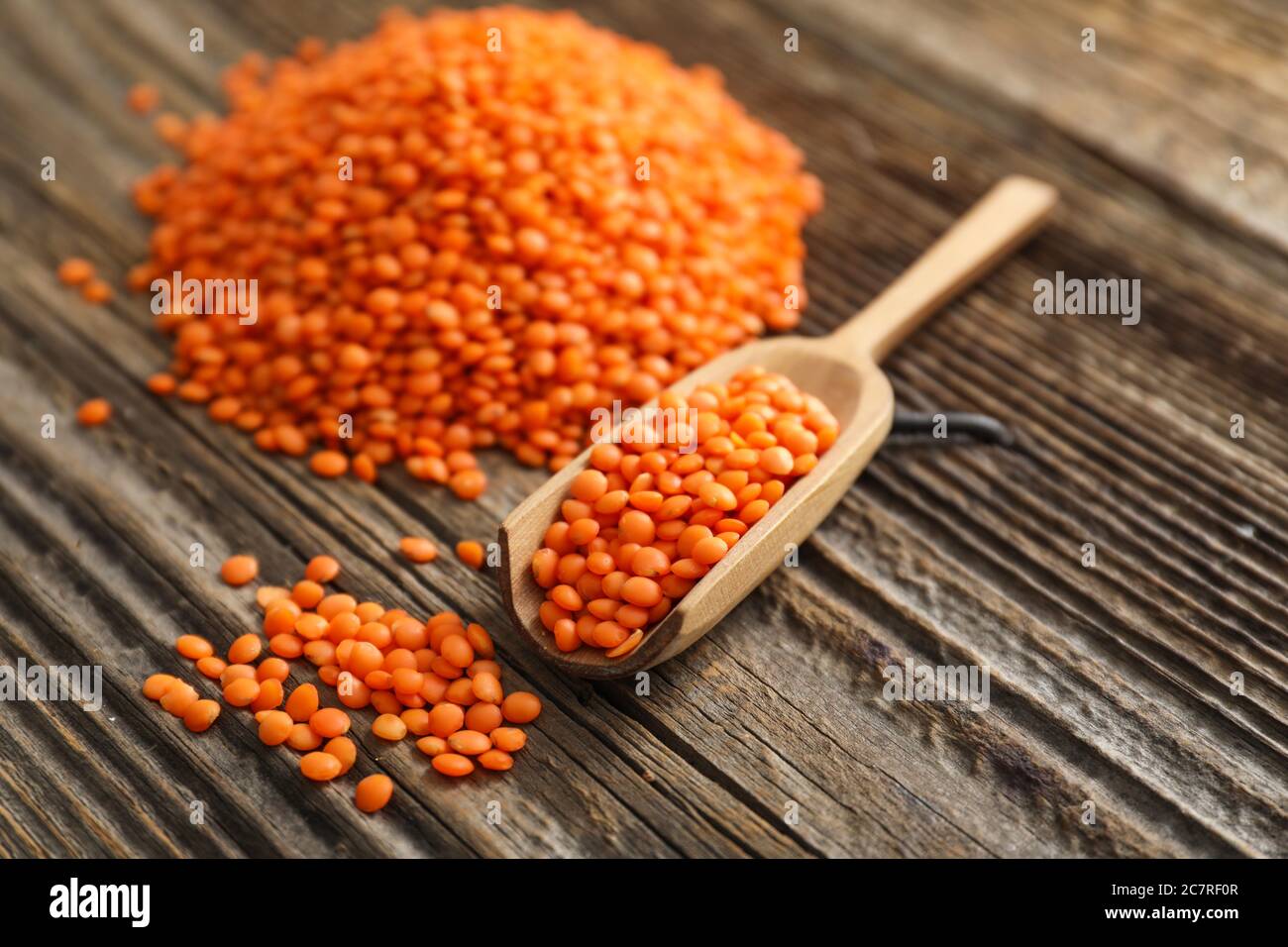 Scoop with red lentils on wooden background Stock Photo
