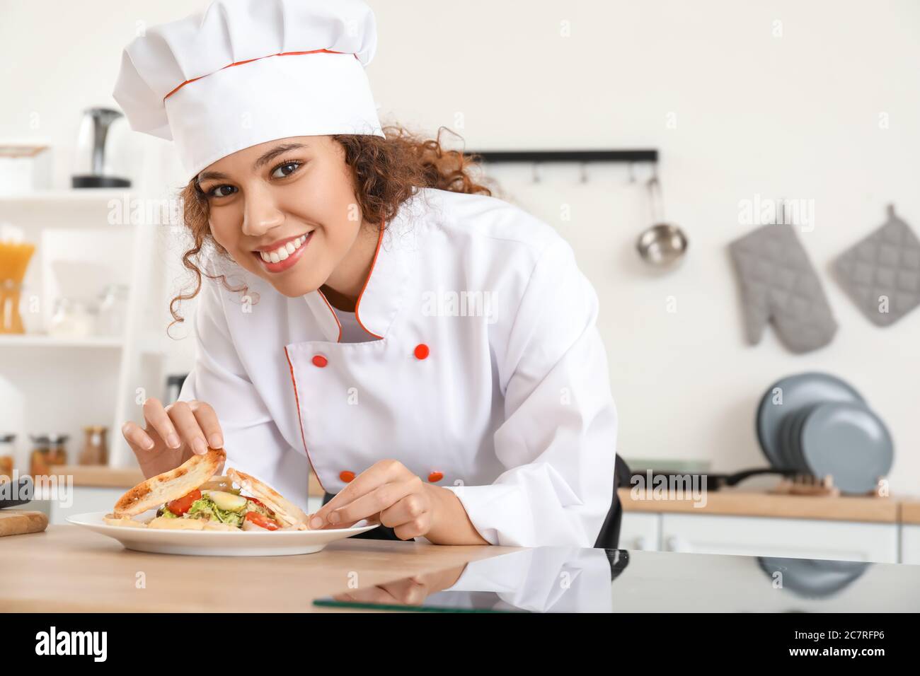 Female African-American chef with tasty dish in kitchen Stock Photo