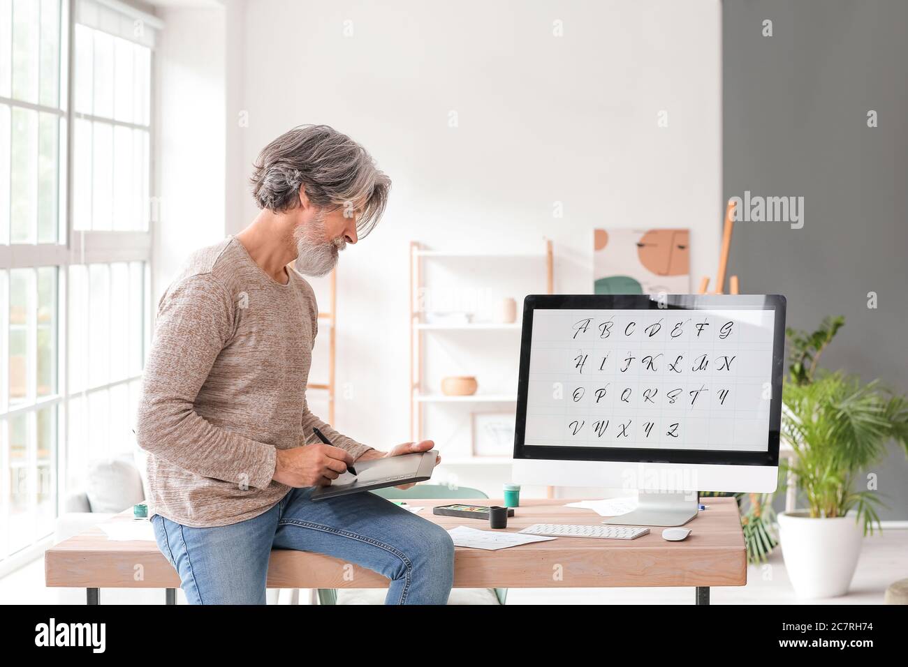 Senior male calligraphist working in office Stock Photo
