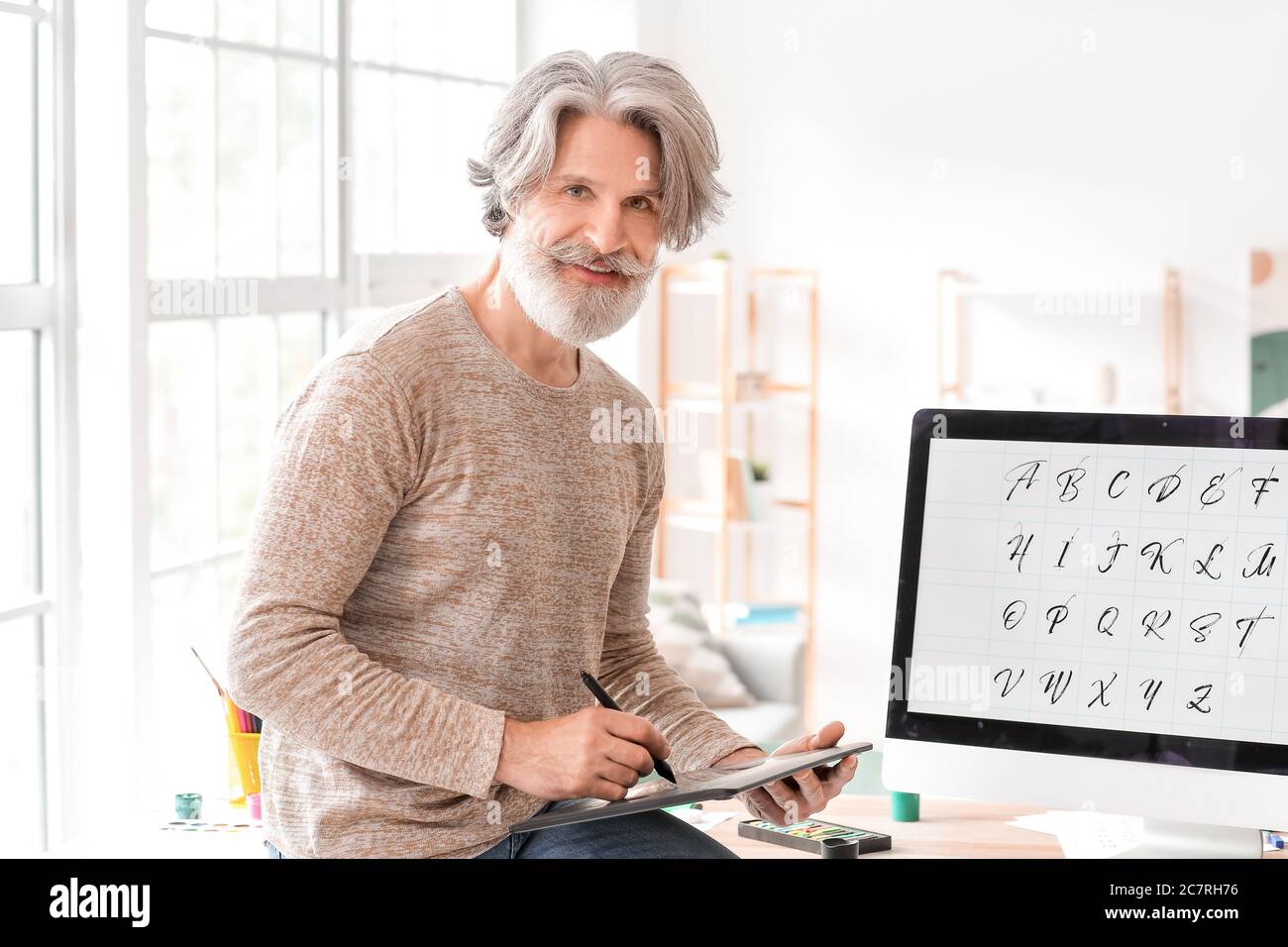 Senior male calligraphist working in office Stock Photo