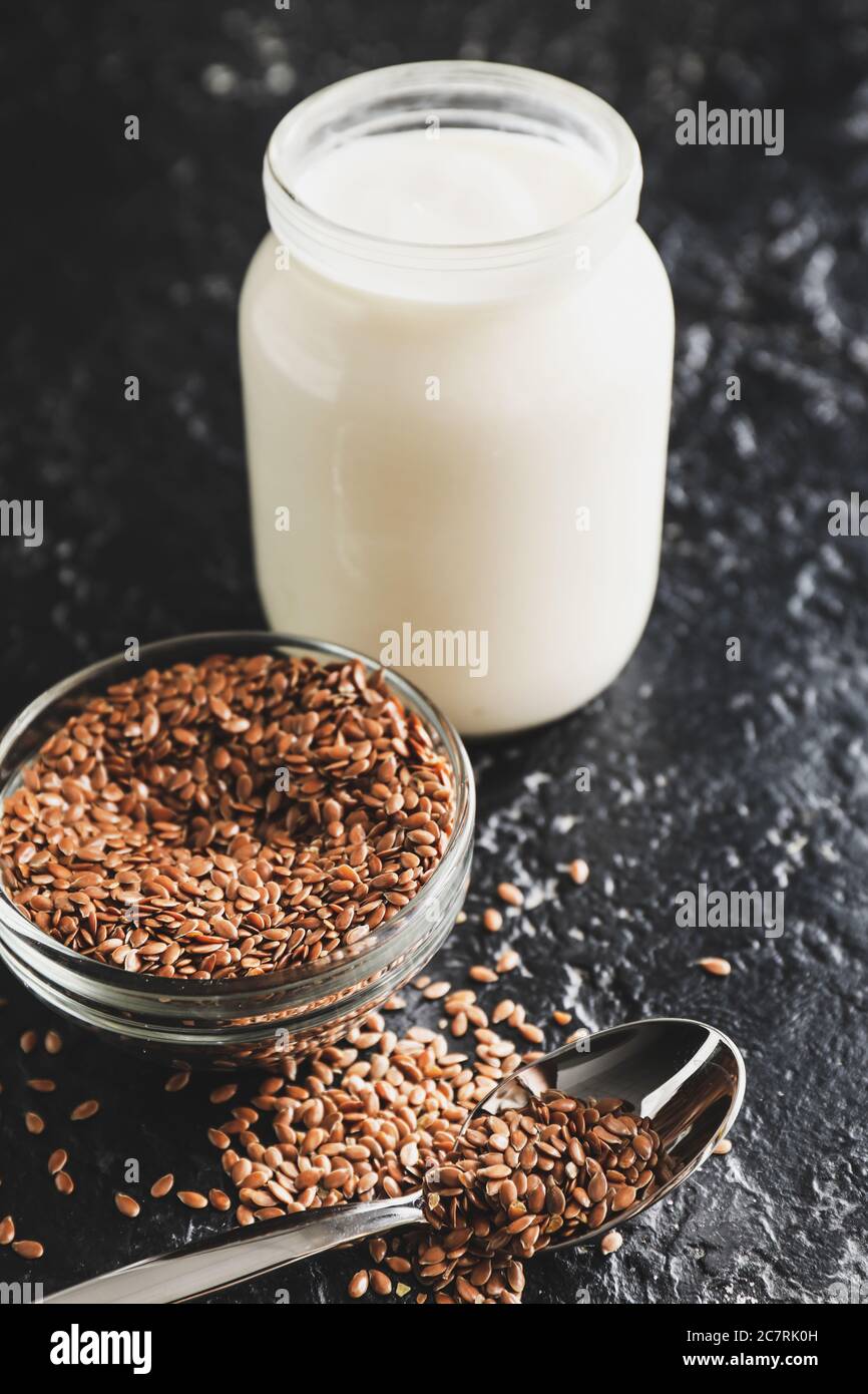 Jar of yogurt and flax seeds on dark background Stock Photo