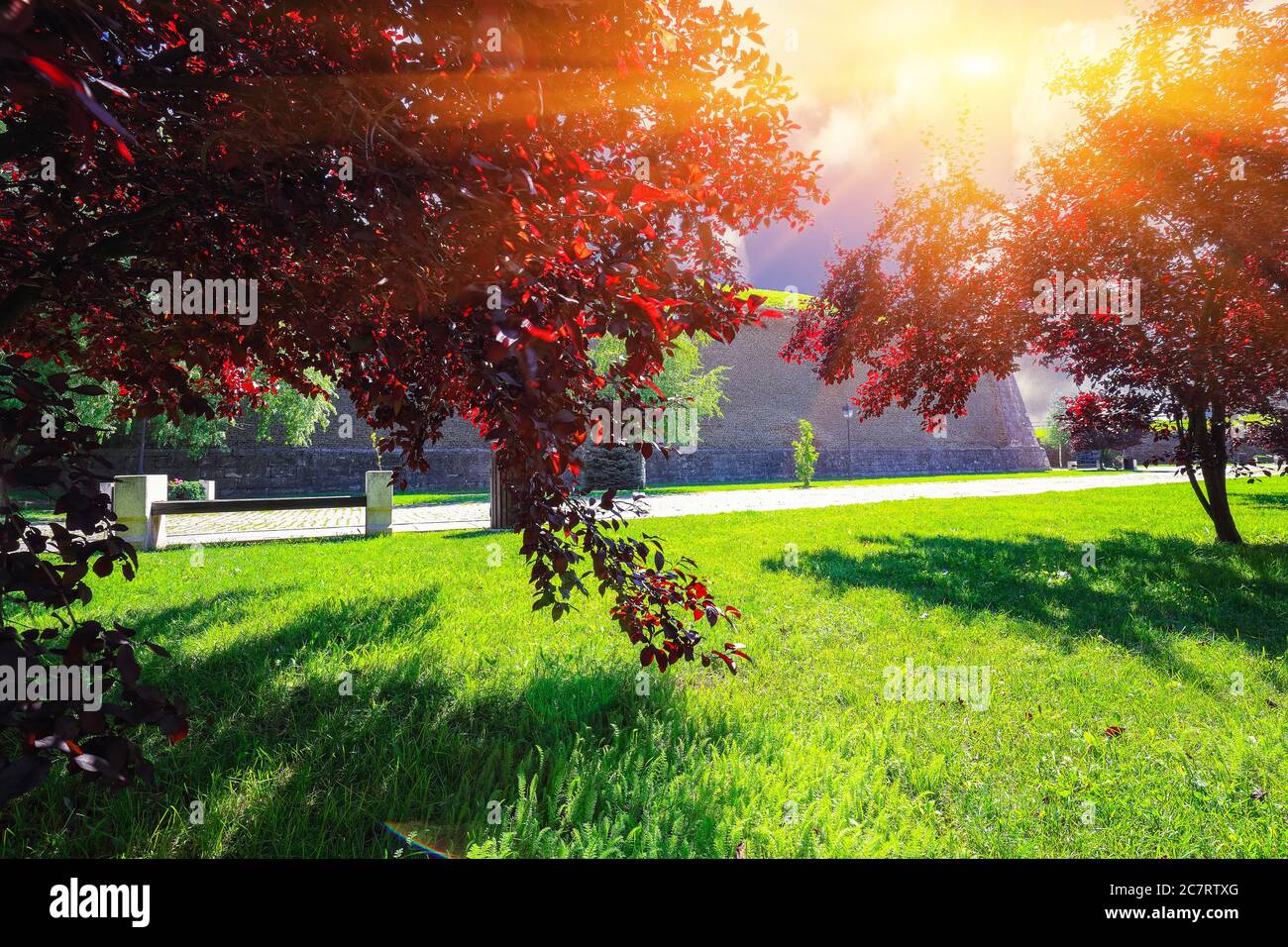 Scene with aged medieval defense fortification walls green lawn and red ornamental trees. Dramatic  summer scene of Transylvania, Alba Iulia city, Rom Stock Photo