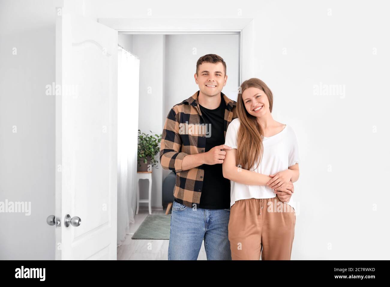 Happy couple in front of door at their new home Stock Photo - Alamy
