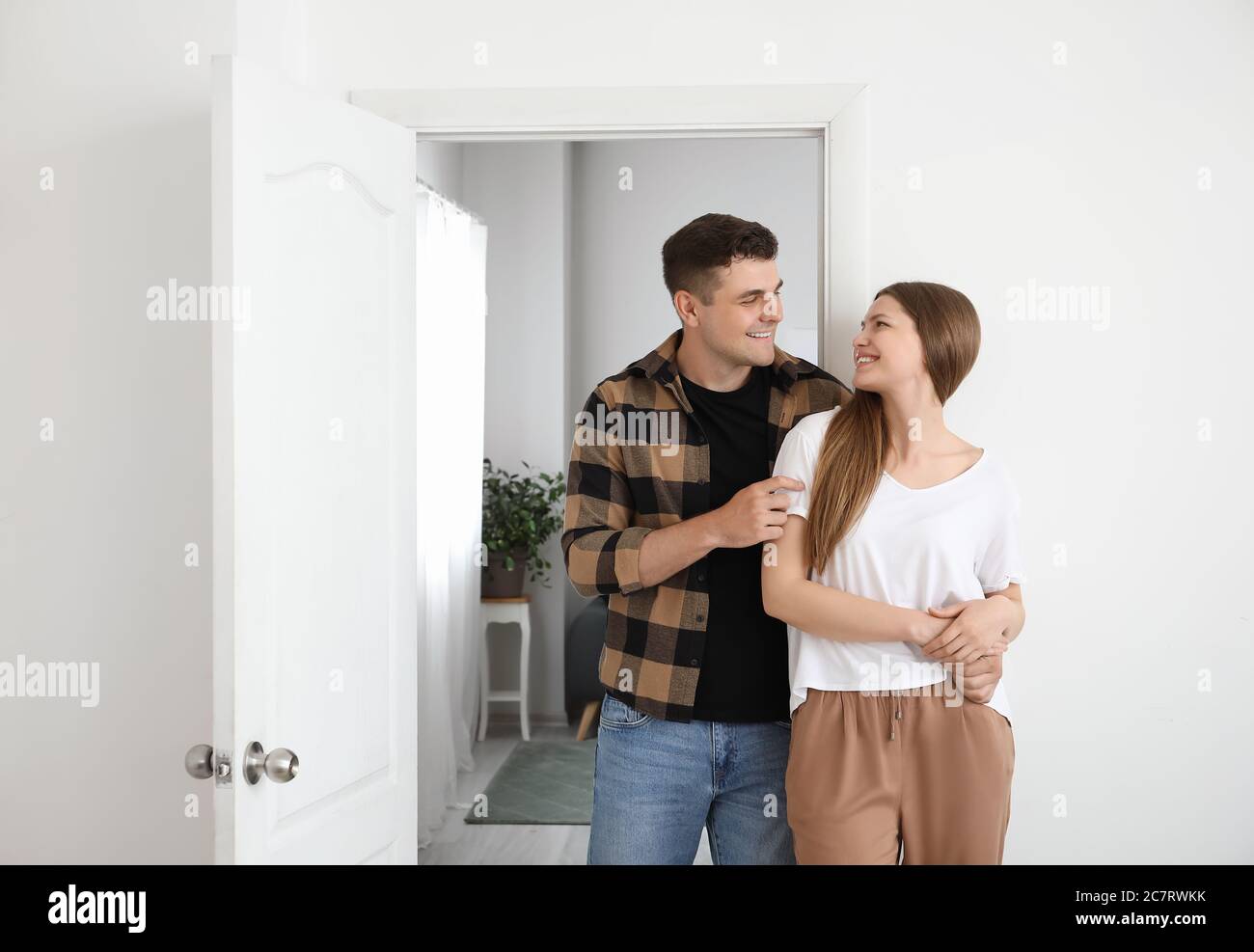 Happy couple in front of door at their new home Stock Photo - Alamy