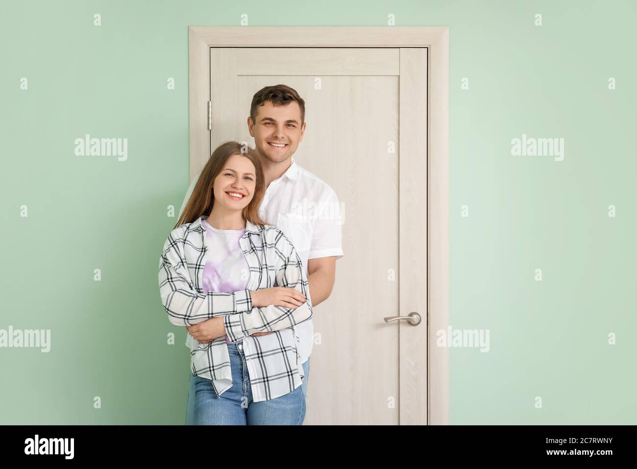 Happy couple in front of door at their new home Stock Photo - Alamy