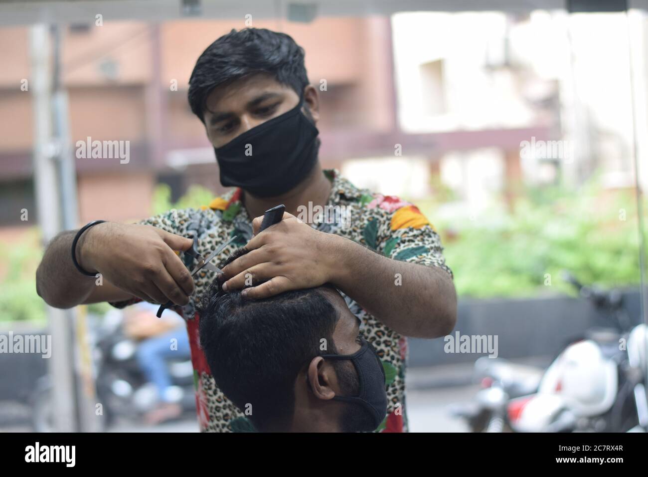 Hyderabad, Telangana, India. june292020 A hairdresser, wearing a protective face mask, works