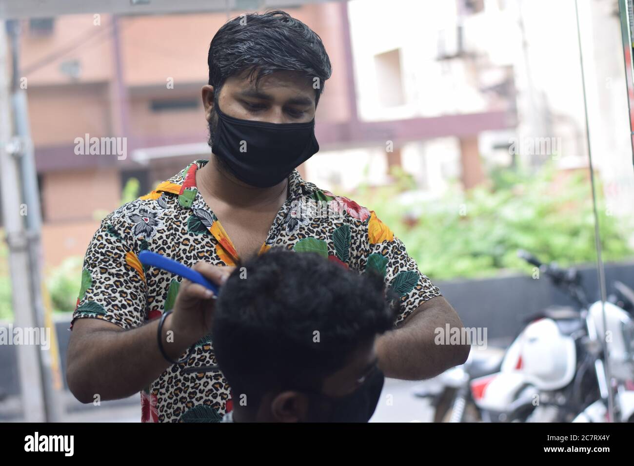 Hyderabad, Telangana, India. june292020 A hairdresser, wearing a protective face mask, works