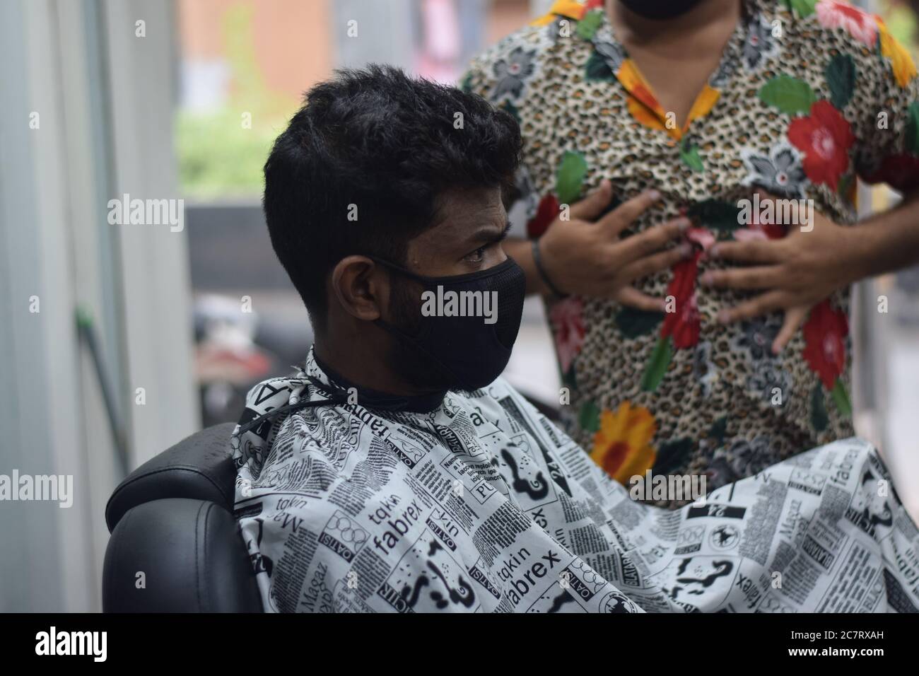Hyderabad, Telangana, India. june292020 A hairdresser, wearing a protective face mask, works