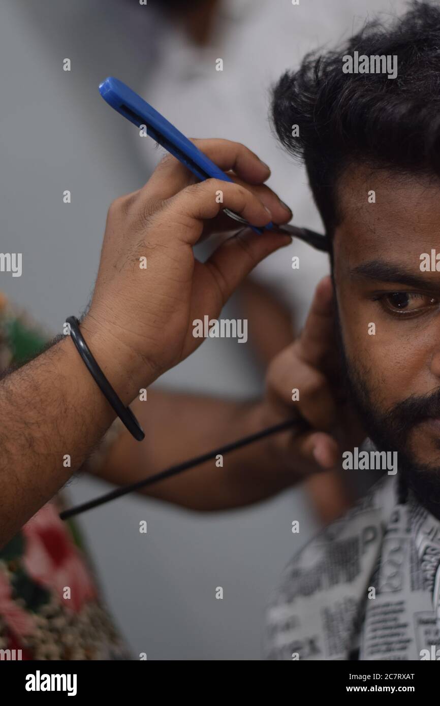 Hyderabad, Telangana, India. june292020 A hairdresser, wearing a protective face mask, works