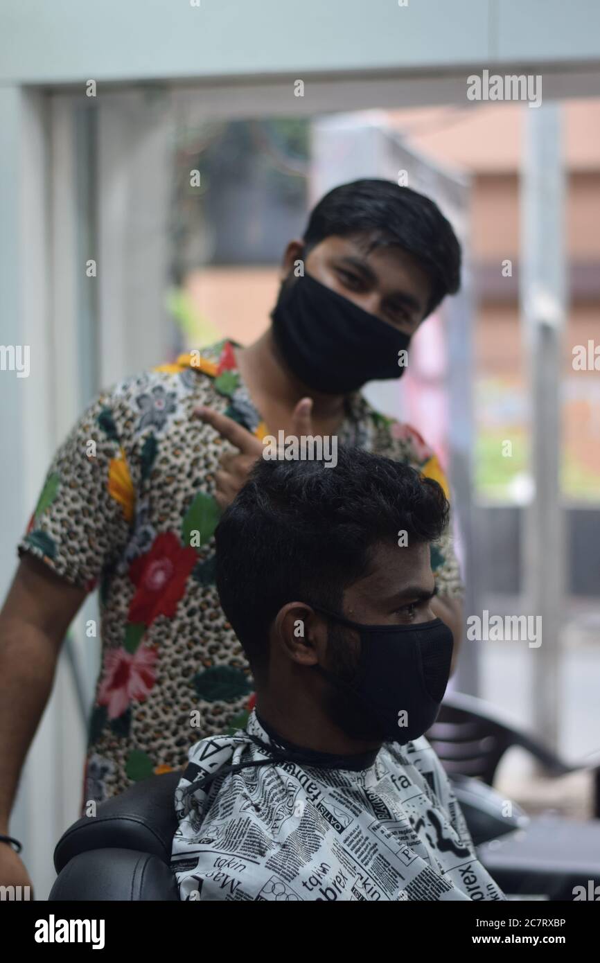 Hyderabad, Telangana, India. june292020 A hairdresser, wearing a protective face mask, works