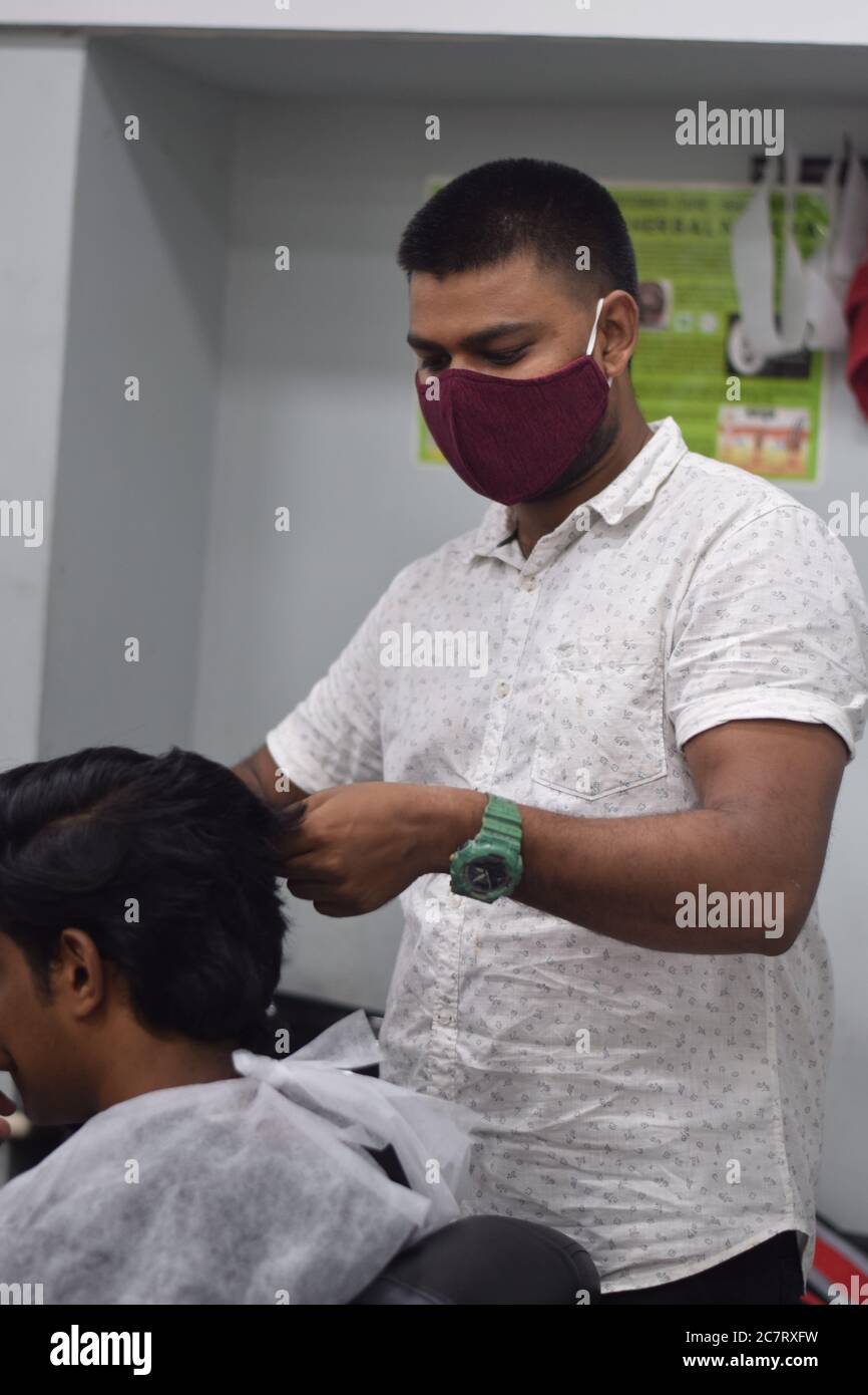 Hyderabad, Telangana, India. june292020 A hairdresser, wearing a protective face mask, works