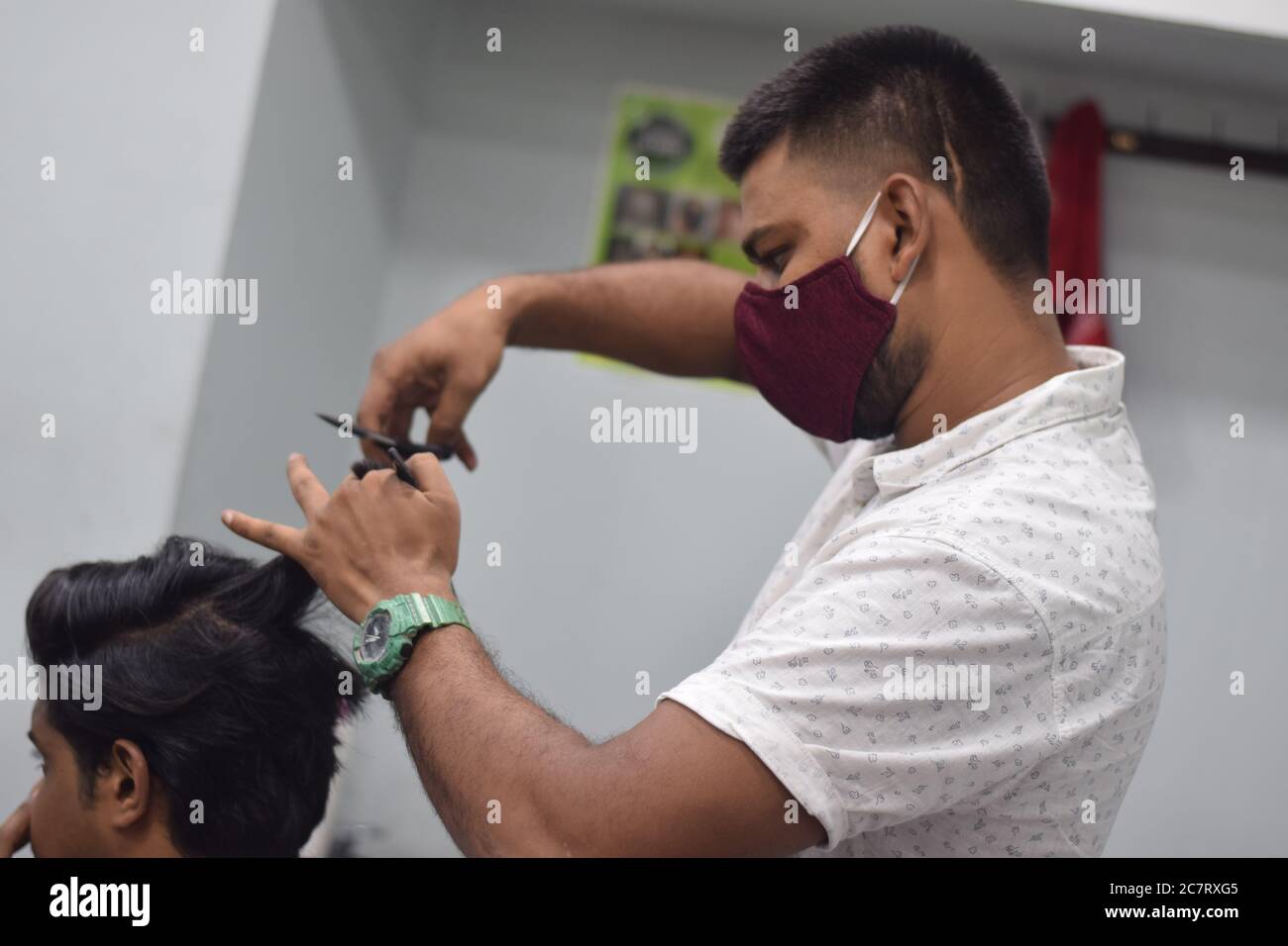 Hyderabad, Telangana, India. june292020 A hairdresser, wearing a protective face mask, works