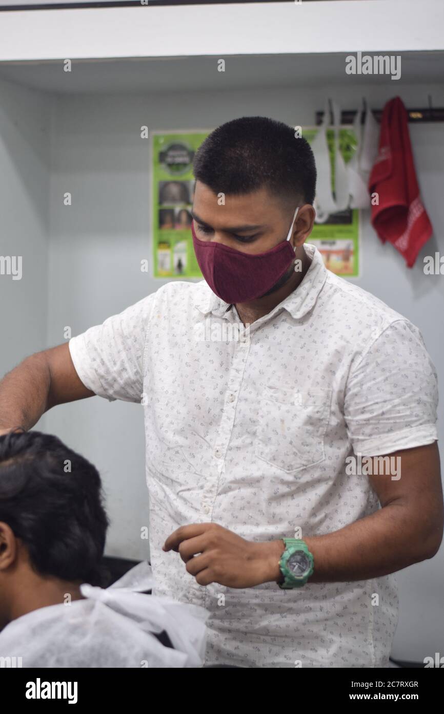 Hyderabad, Telangana, India. june292020 A hairdresser, wearing a protective face mask, works