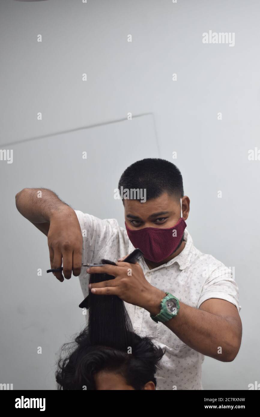 Hyderabad, Telangana, India. june292020 A hairdresser, wearing a protective face mask, works