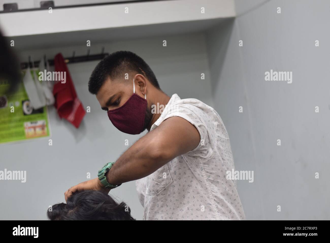 Hyderabad, Telangana, India. june292020 A hairdresser, wearing a protective face mask, works