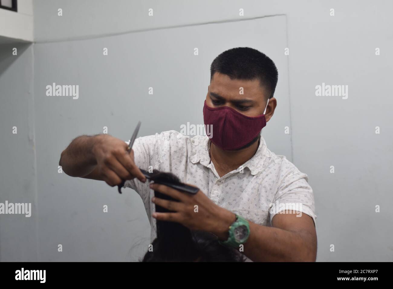 Hyderabad, Telangana, India. june292020 A hairdresser, wearing a protective face mask, works