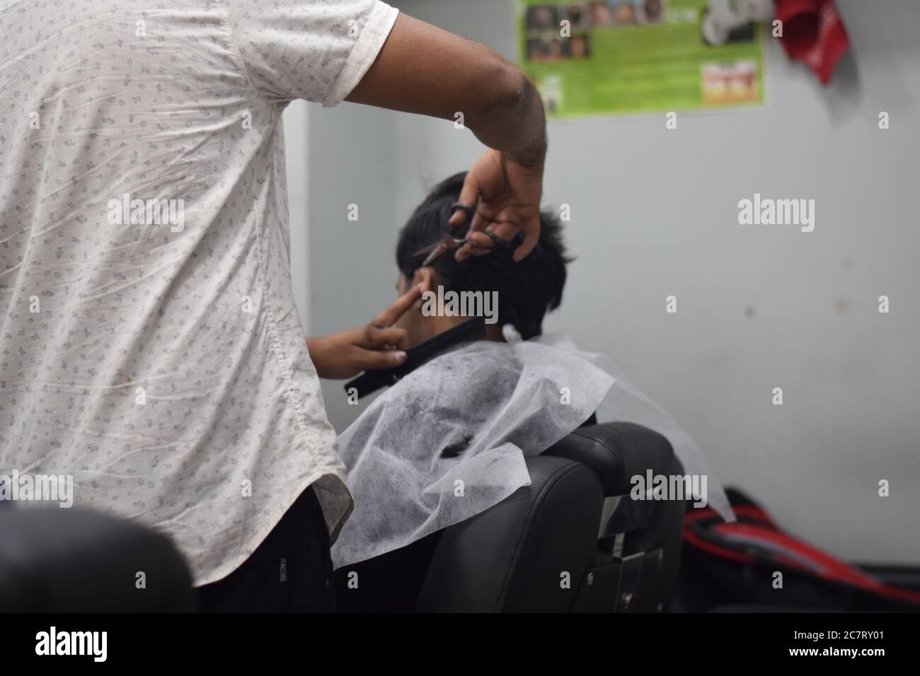 Hyderabad, Telangana, India. june292020 A hairdresser, wearing a protective face mask, works