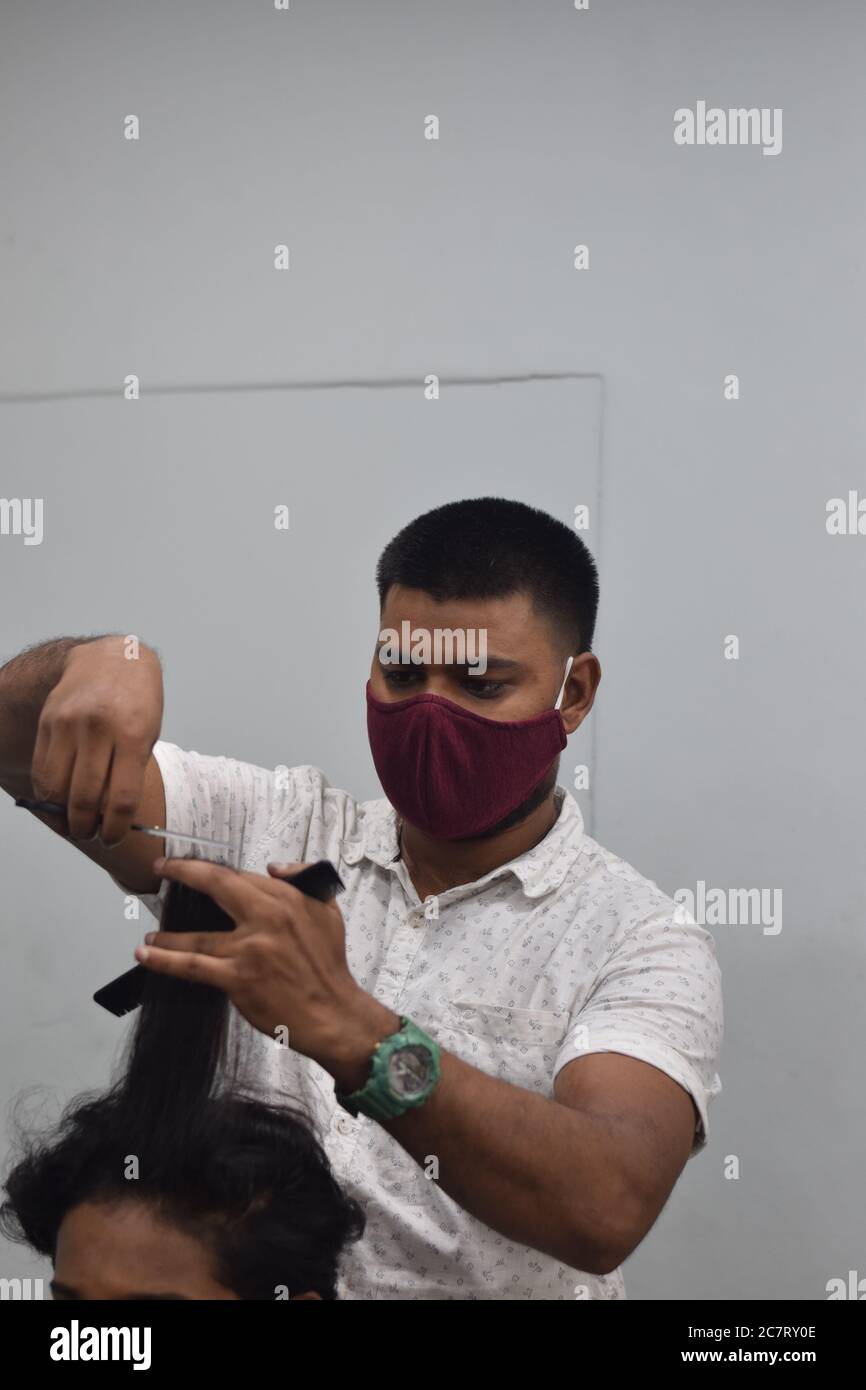 Hyderabad, Telangana, India. june292020 A hairdresser, wearing a protective face mask, works