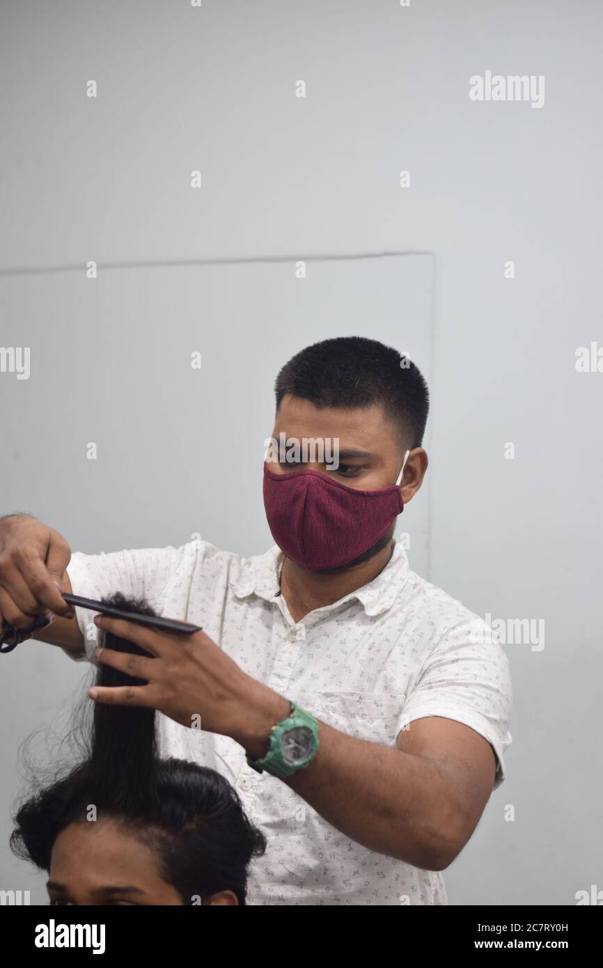 Hyderabad, Telangana, India. june292020 A hairdresser, wearing a protective face mask, works