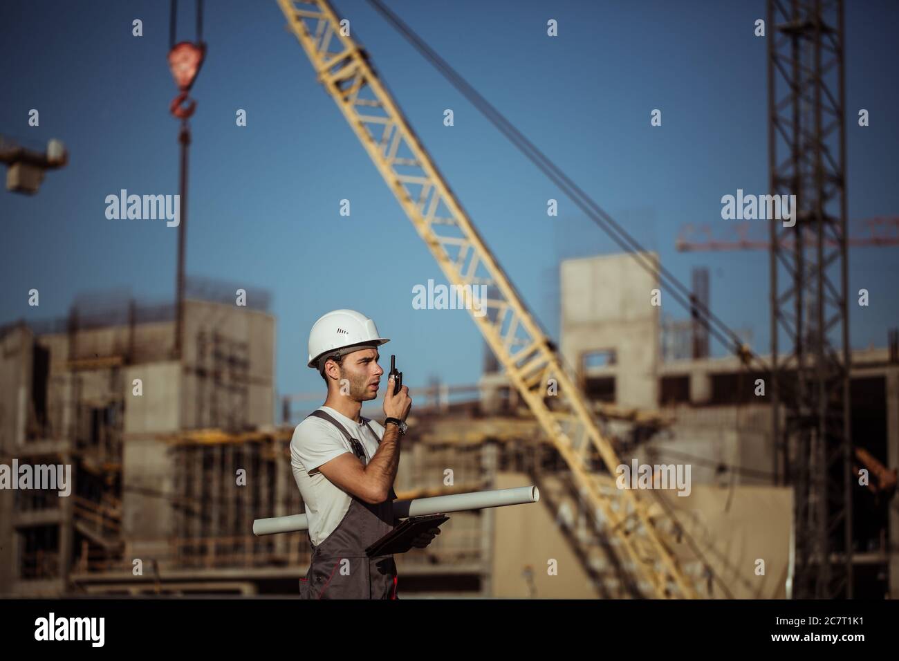 Engineer builder using tablet and walkie talkie, giving instructions at a construction site Stock Photo