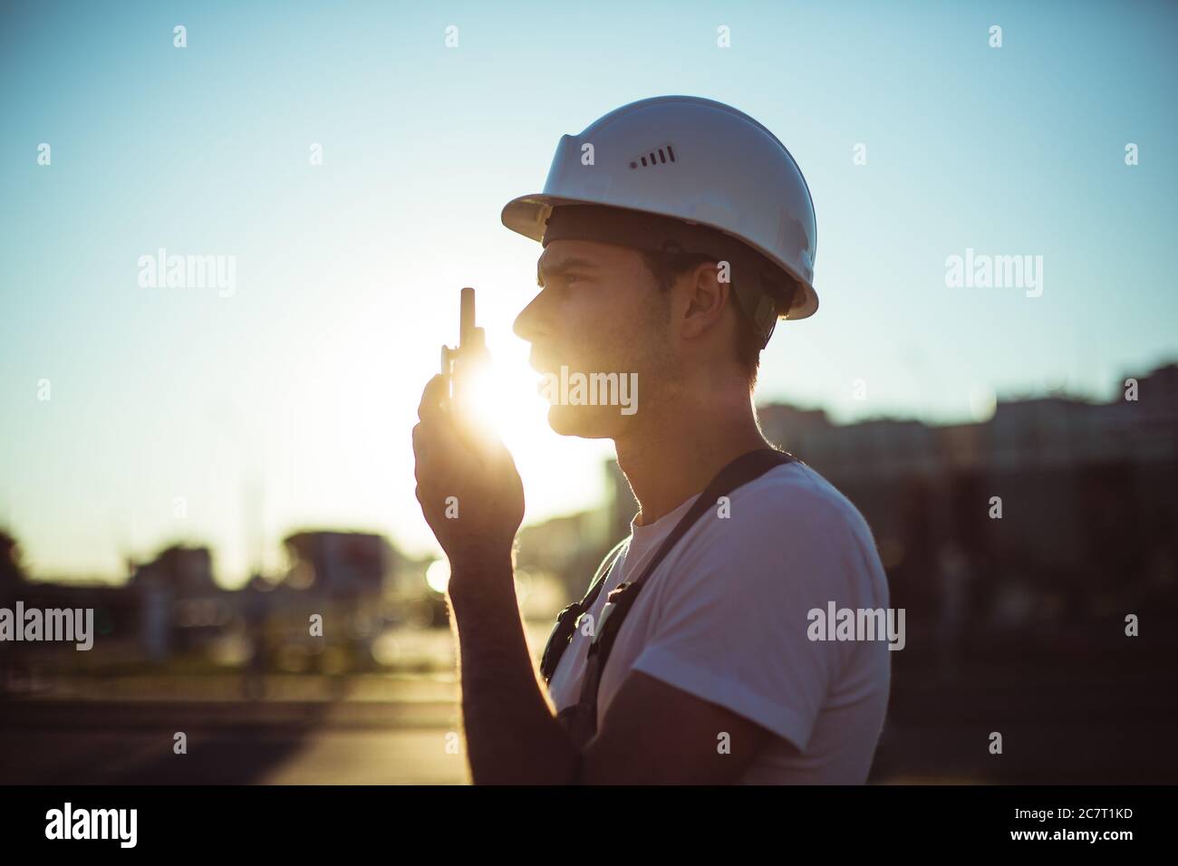 Engineer builder using tablet and walkie talkie, giving instructions at a construction site Stock Photo