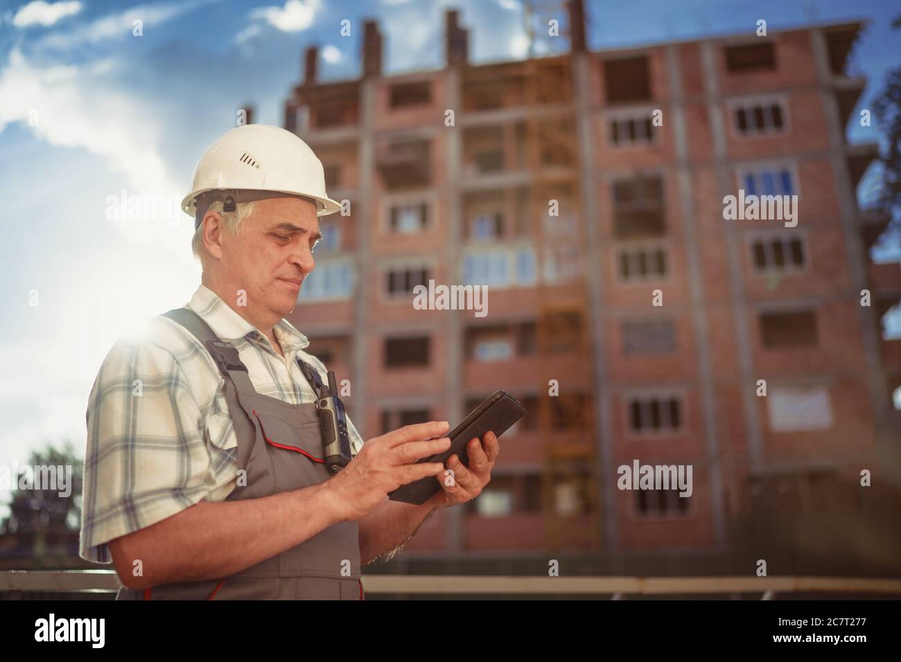 Construction manager controlling building site with pc tablet at sunset Stock Photo