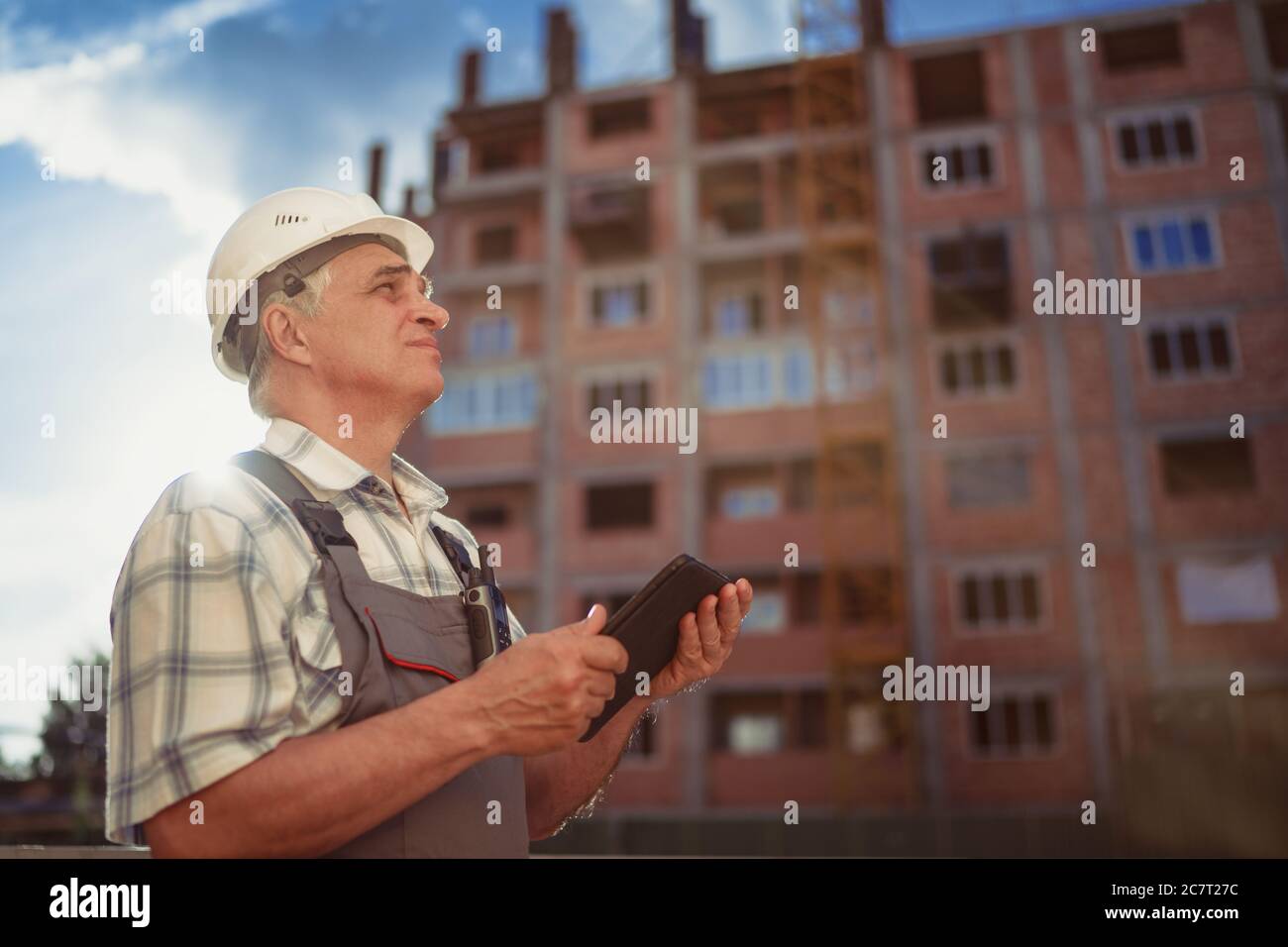 Construction manager controlling building site with pc tablet at sunset Stock Photo