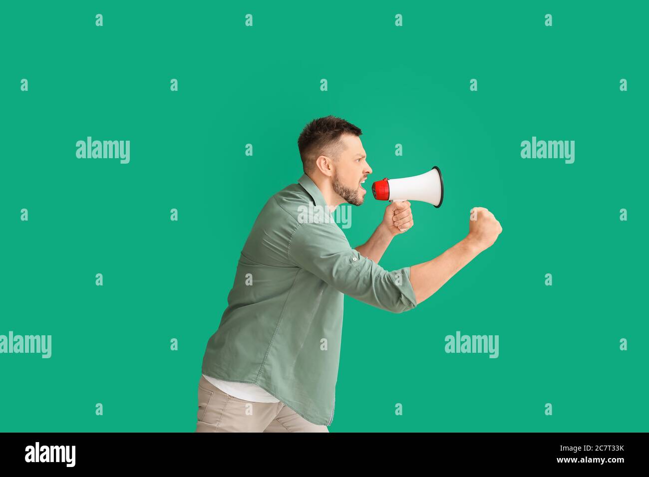 Protesting man with megaphone on color background Stock Photo