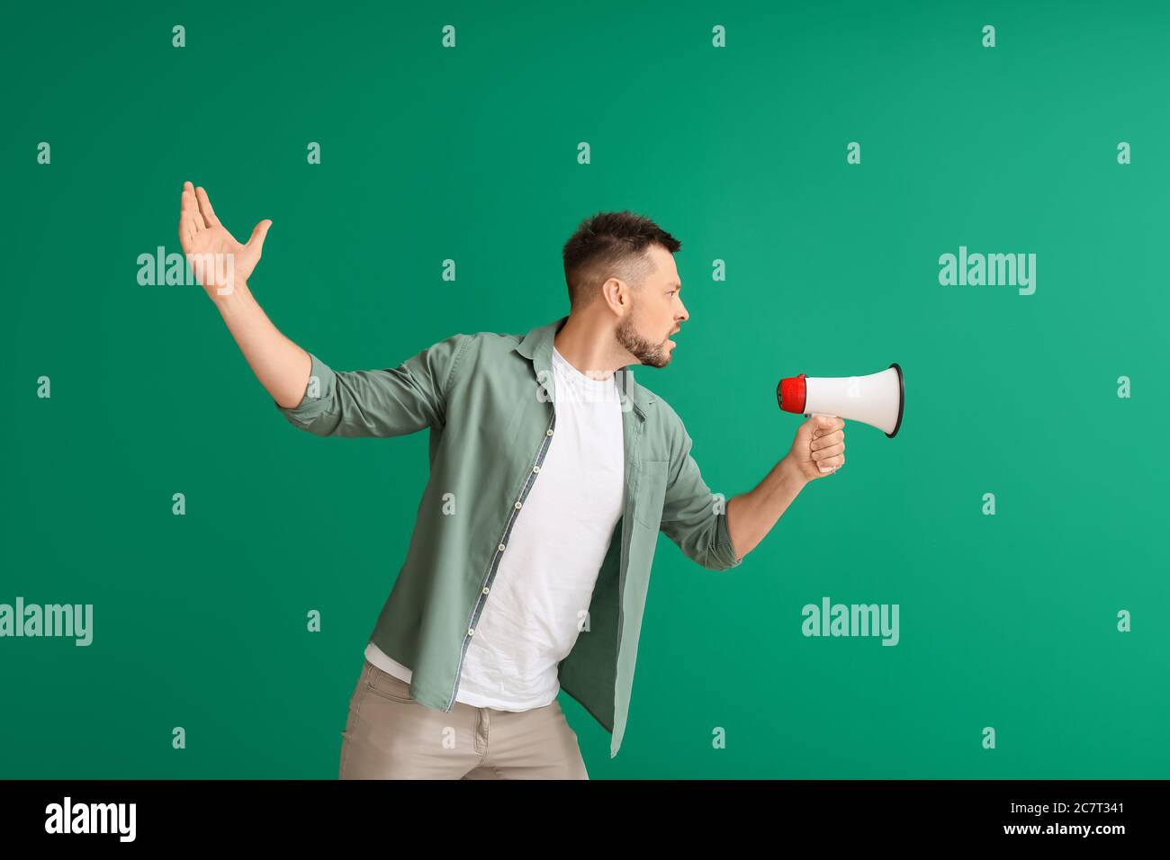 Protesting man with megaphone on color background Stock Photo