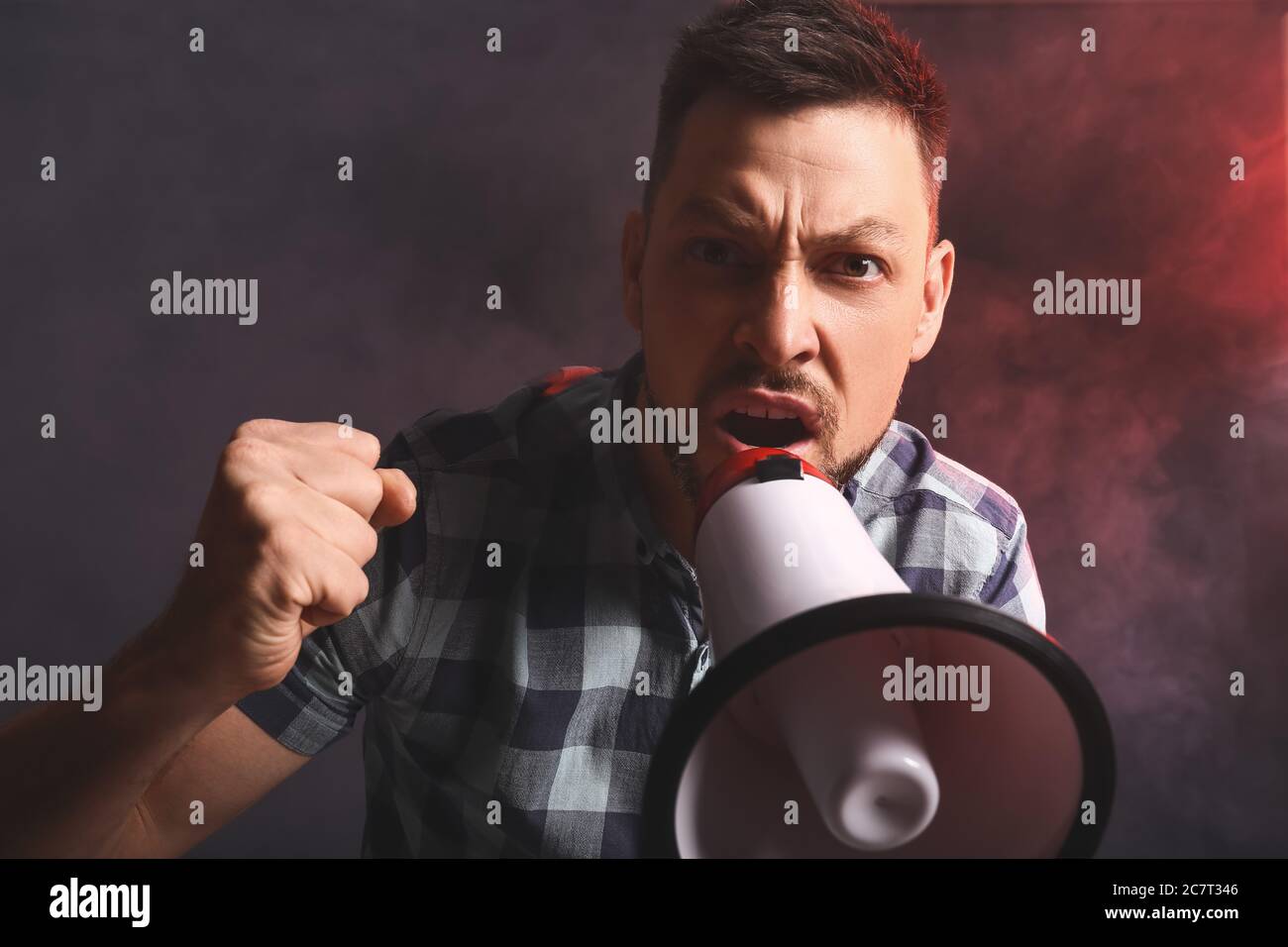 Protesting man with megaphone on dark background Stock Photo