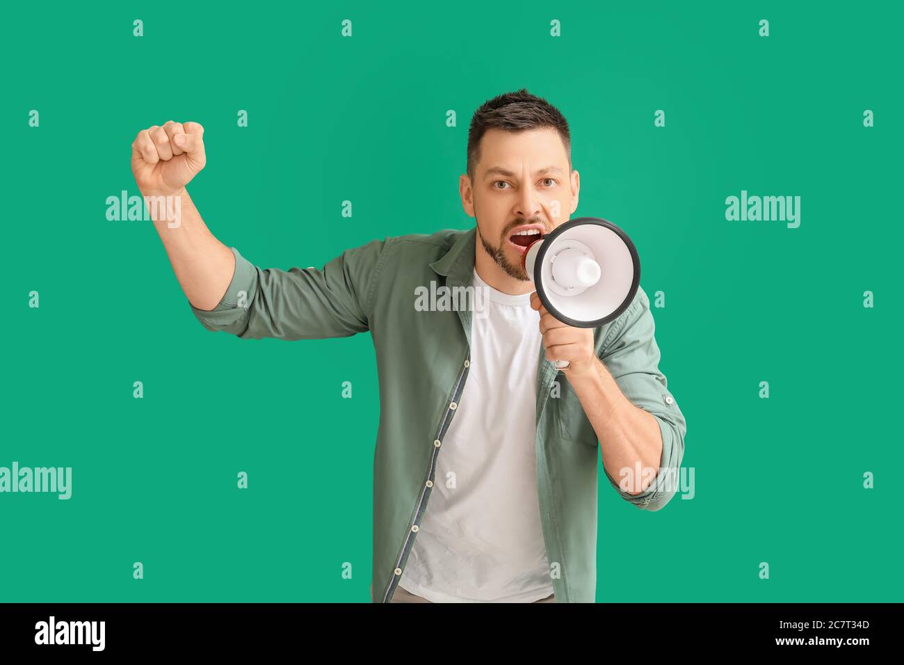 Protesting man with megaphone on color background Stock Photo