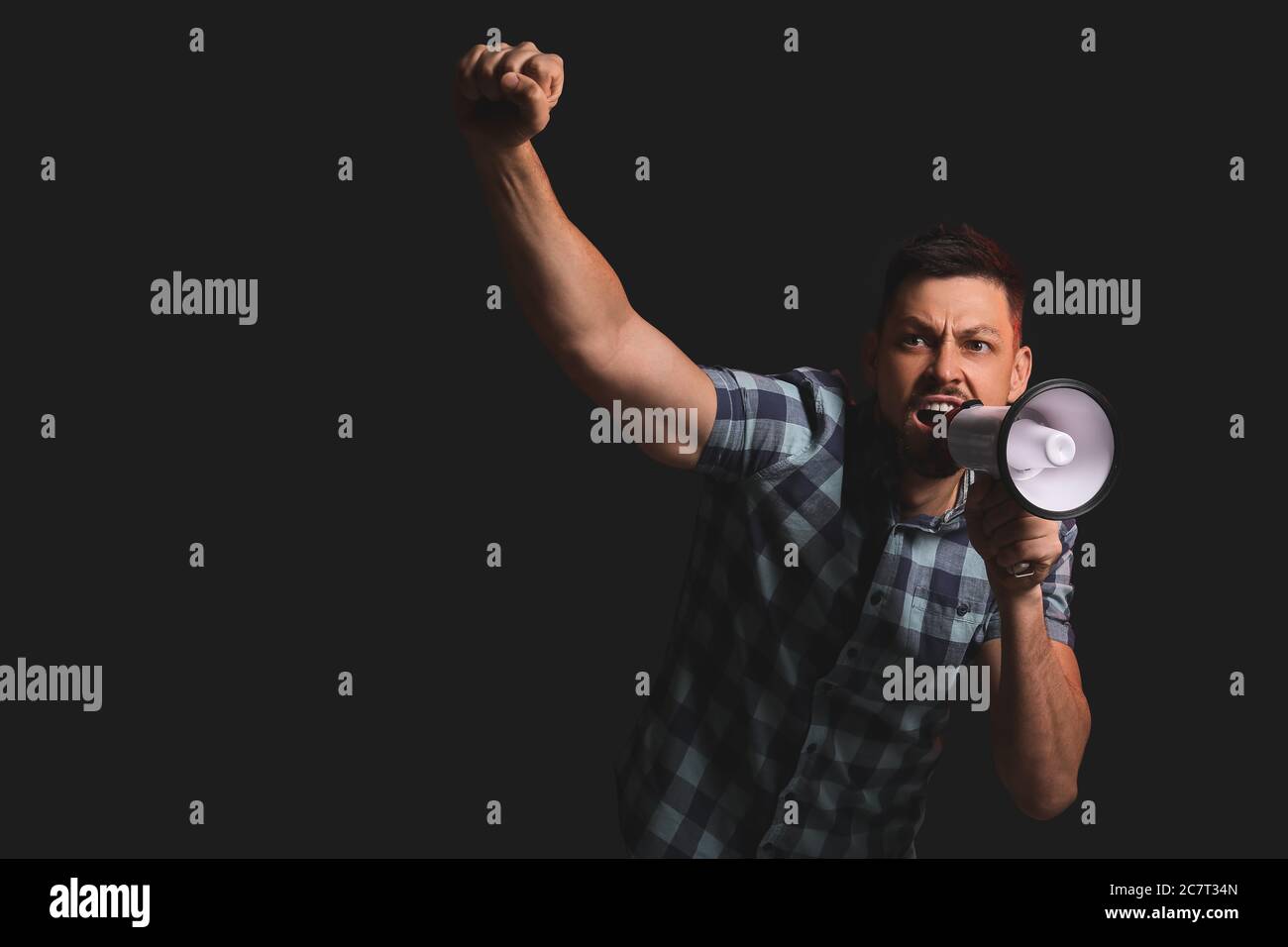 Protesting man with megaphone on dark background Stock Photo