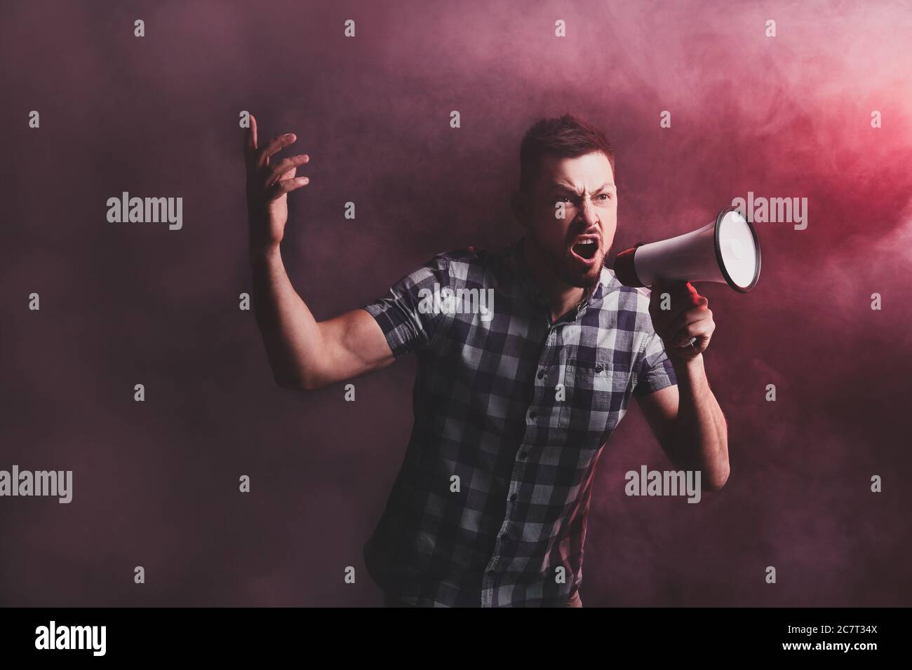 Protesting man with megaphone on dark background Stock Photo