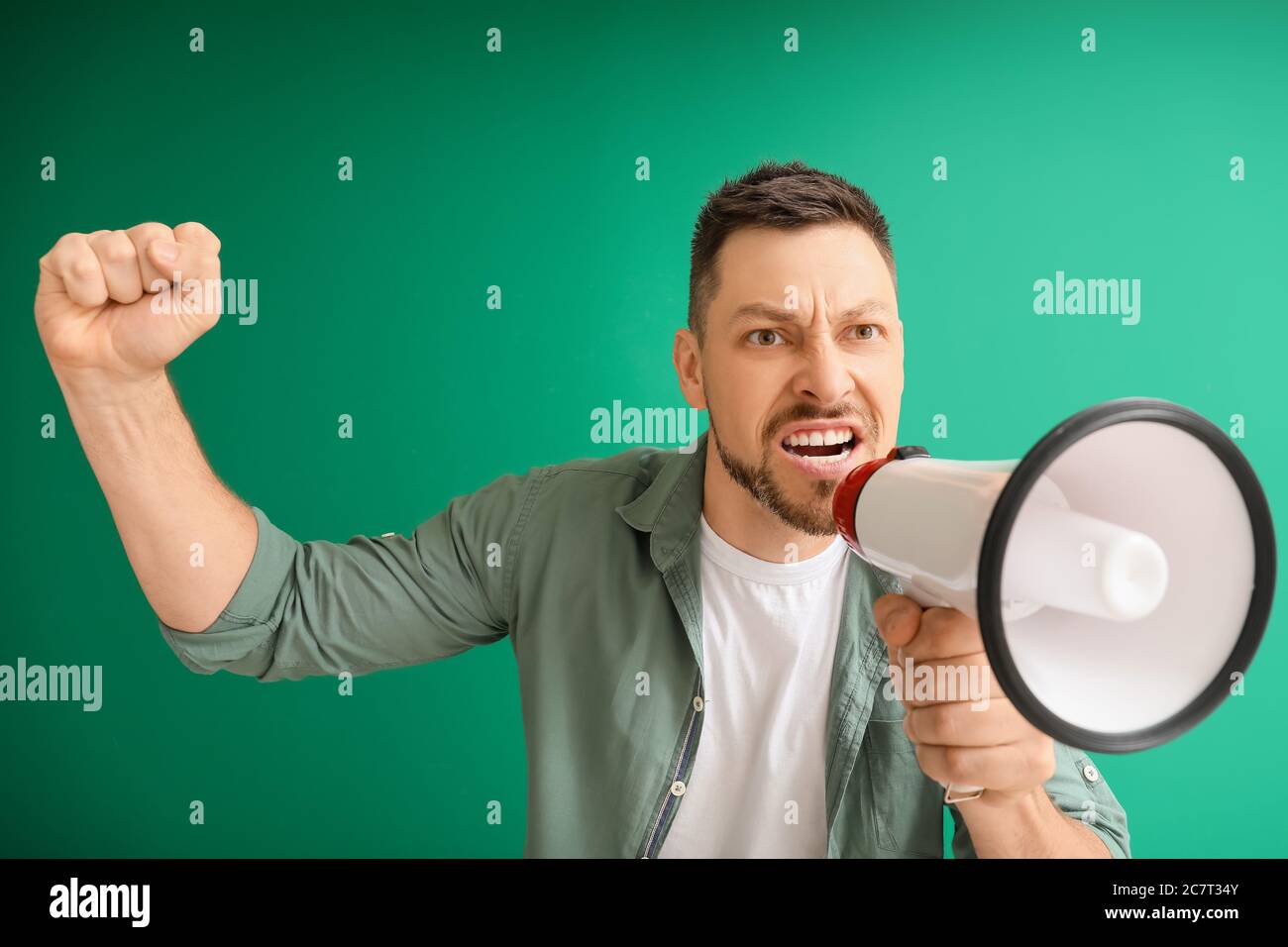 Protesting man with megaphone on color background Stock Photo