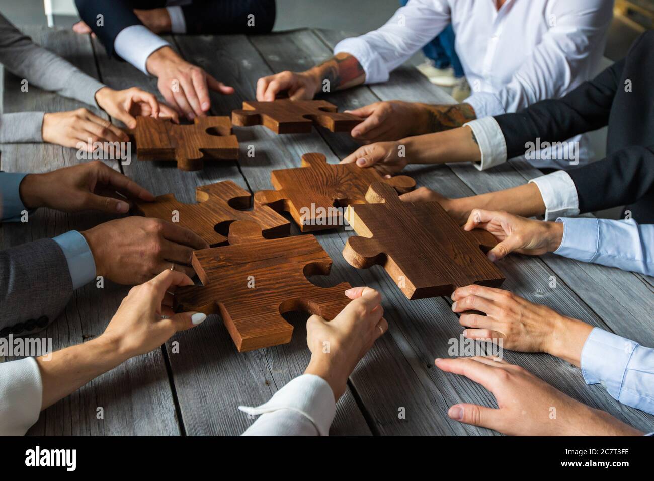 Business people team sitting around meeting table and assembling wooden