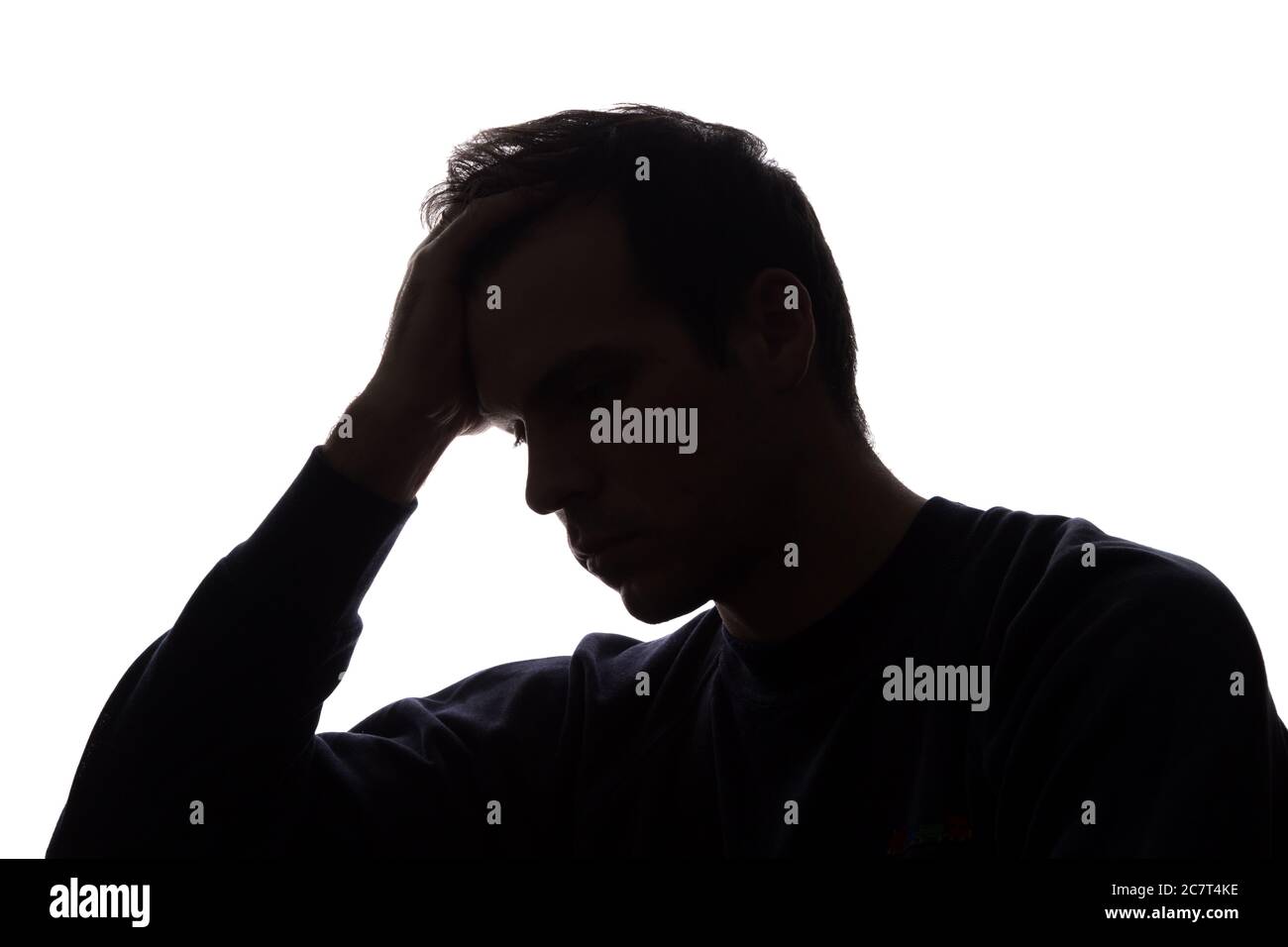 A young man with grief tearing at her hair - silhouette Stock Photo