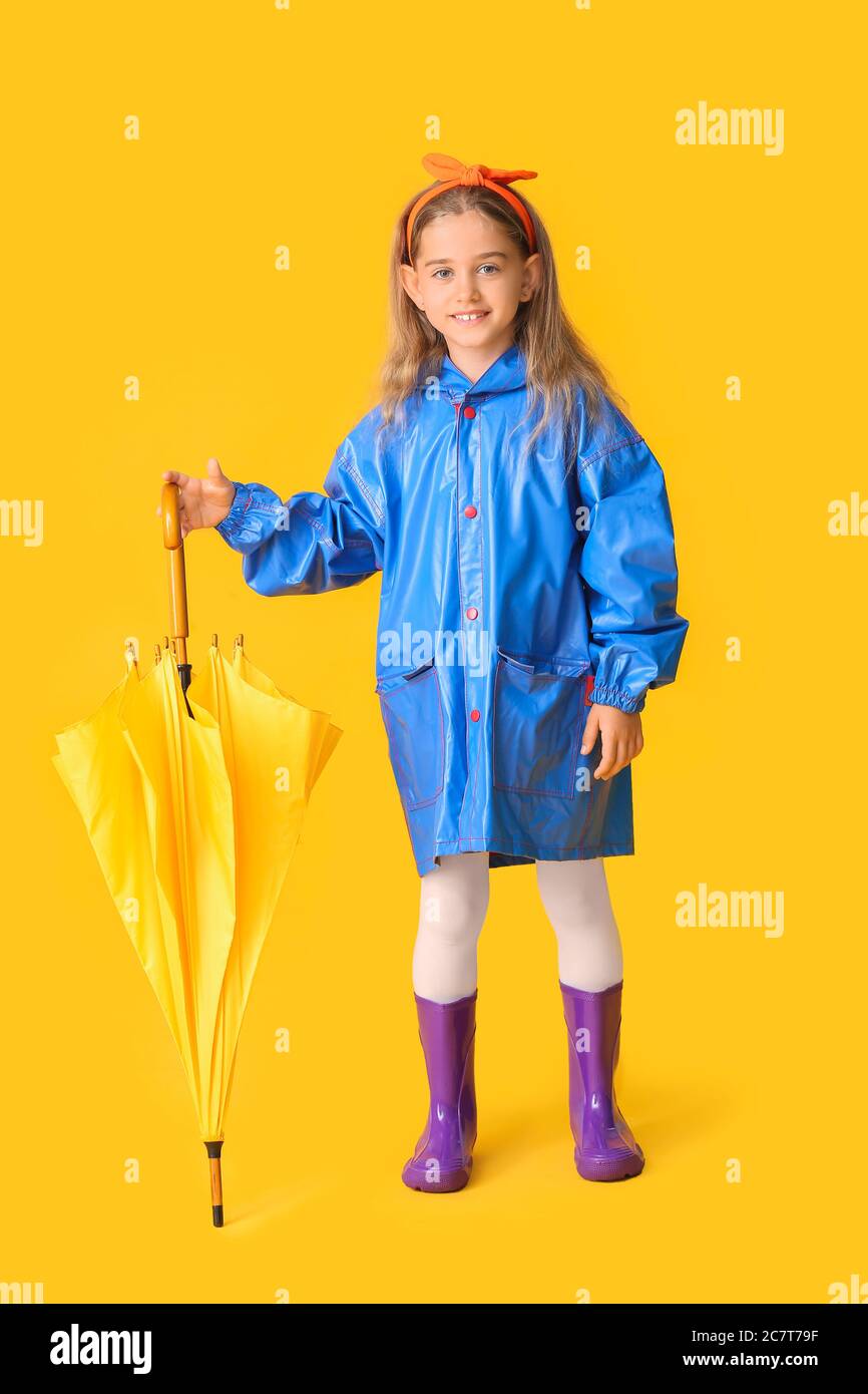 Cute little girl in raincoat and with umbrella on color background