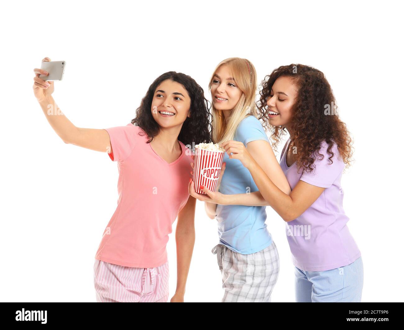 Beautiful young women in pajamas taking selfie on white background ...