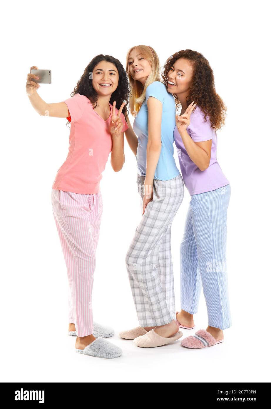 Beautiful young women in pajamas taking selfie on white background ...